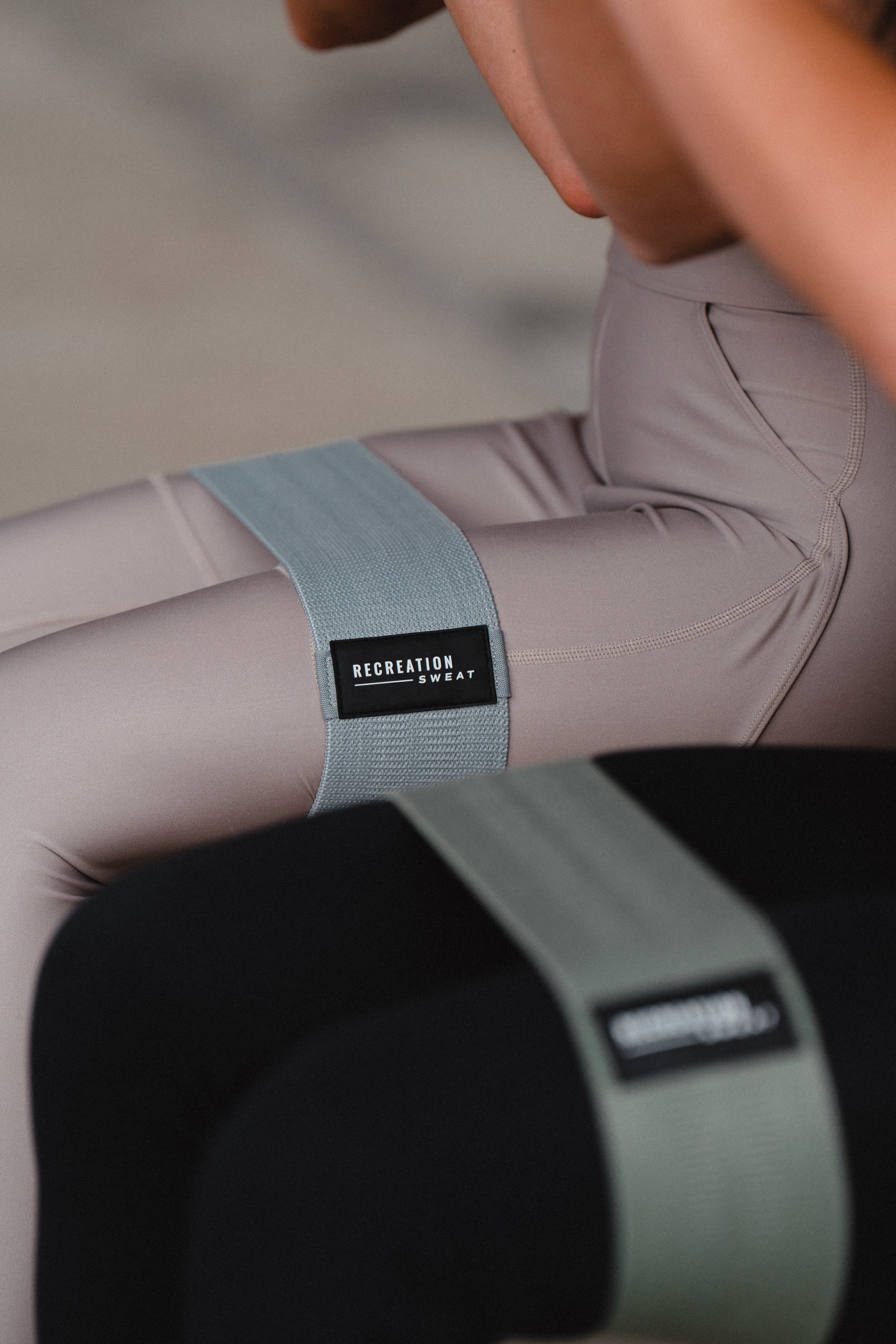 Close-up of a person's leg wearing beige athletic pants with a black and white label that reads 'Recreation Sweat'.