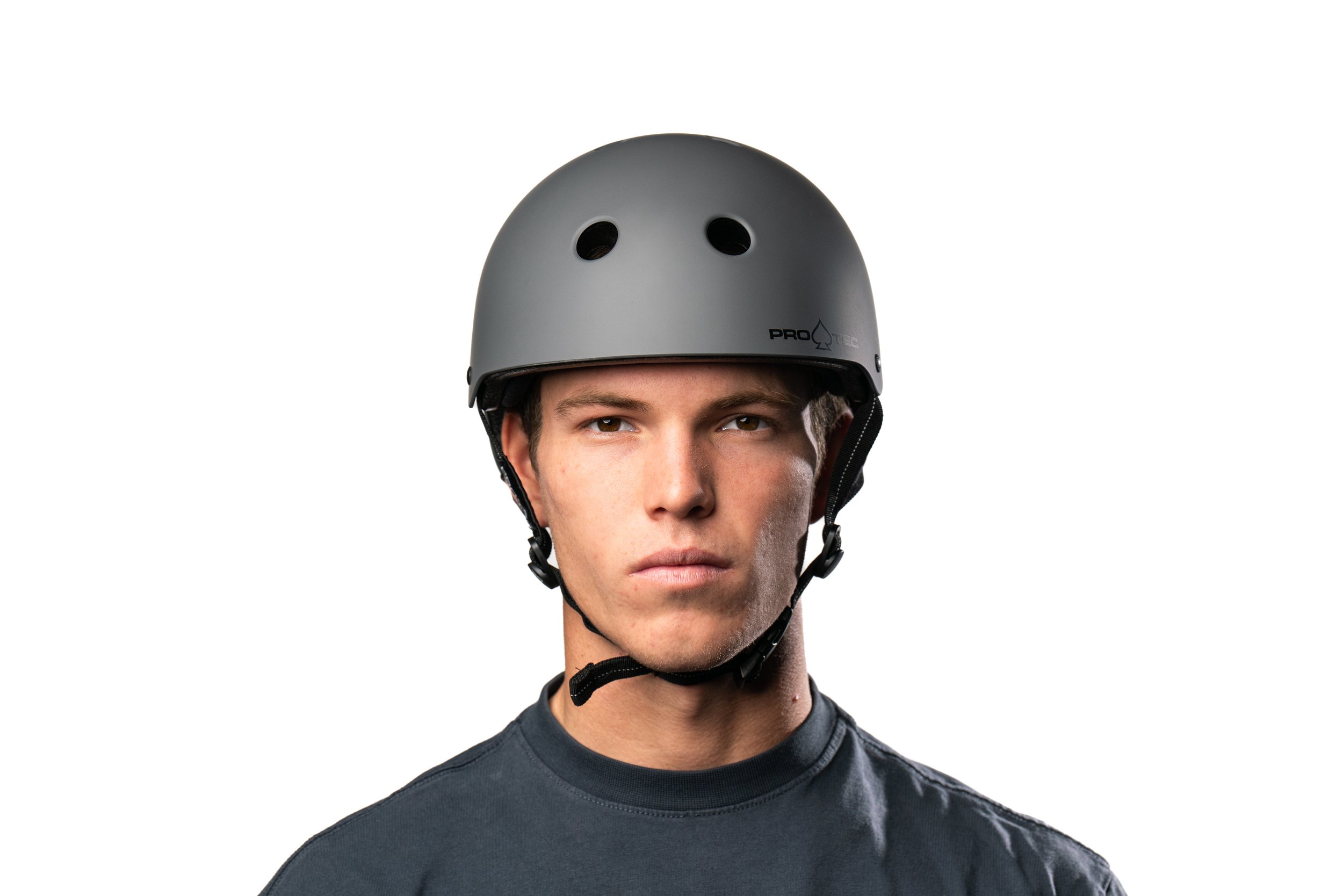 Young man wearing a gray helmet and black shirt, facing forward with a serious expression, white background.