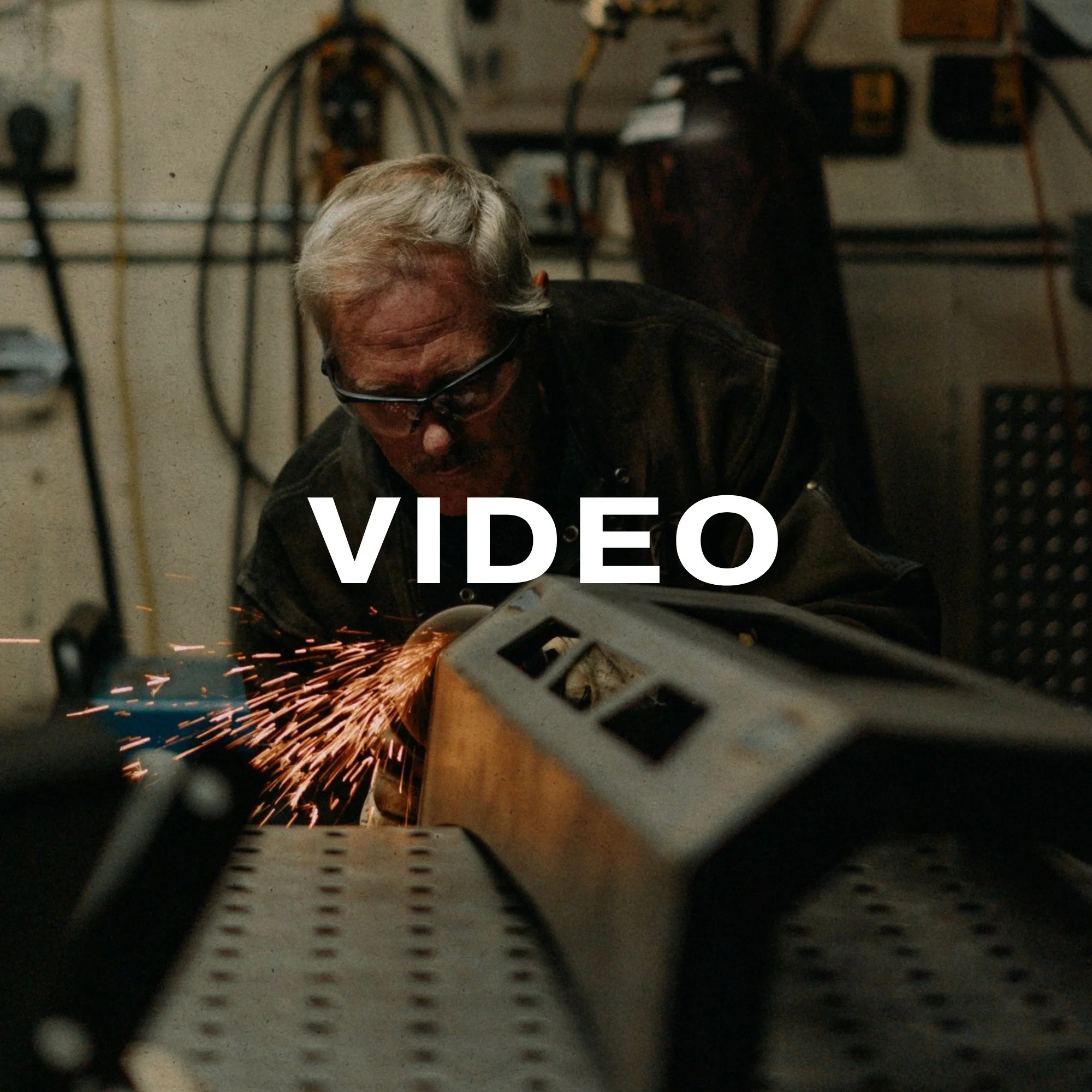 A man welding metal in a workshop, sparks flying as he uses a welding torch.