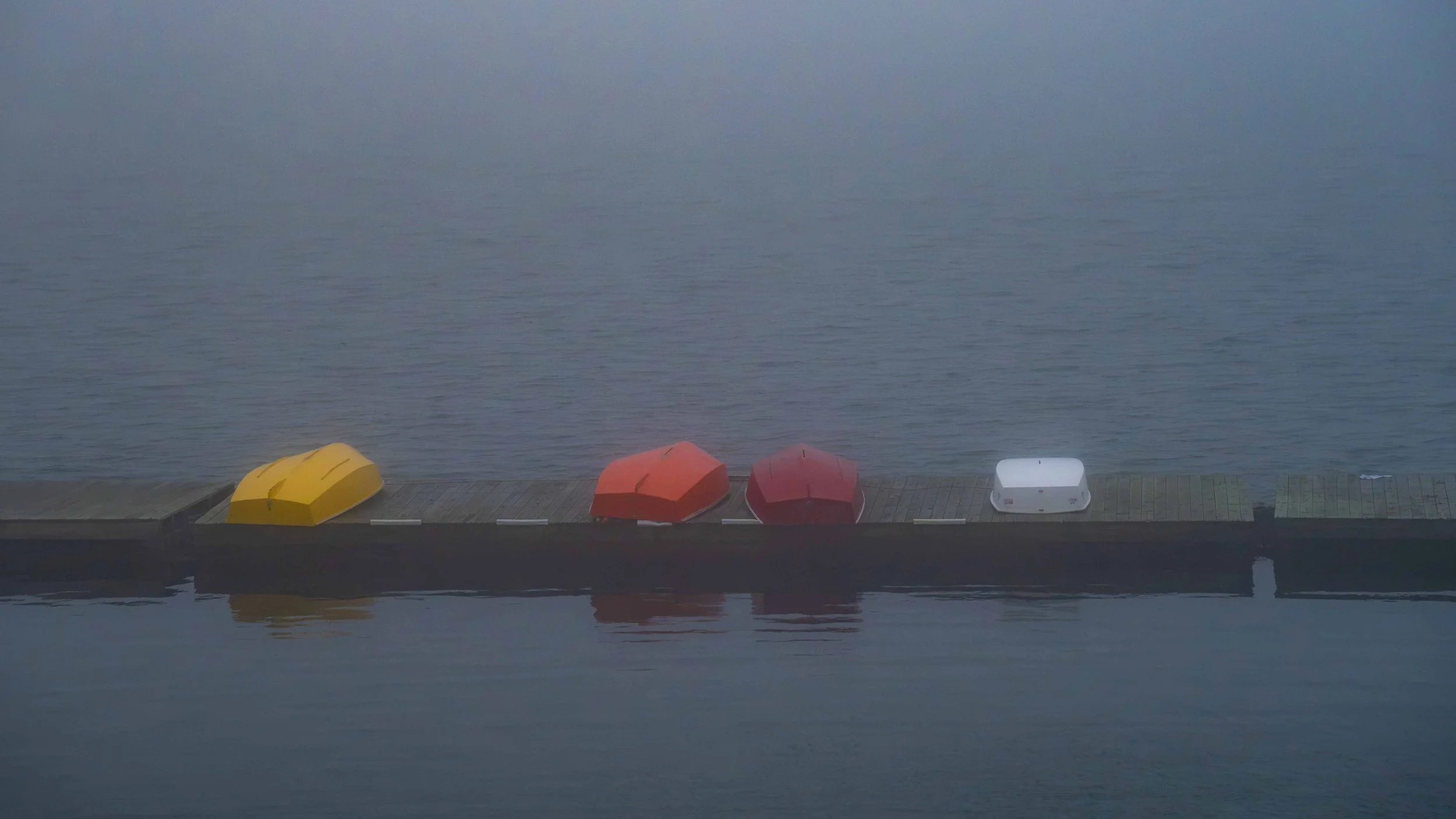 row boats on the dock in the fog