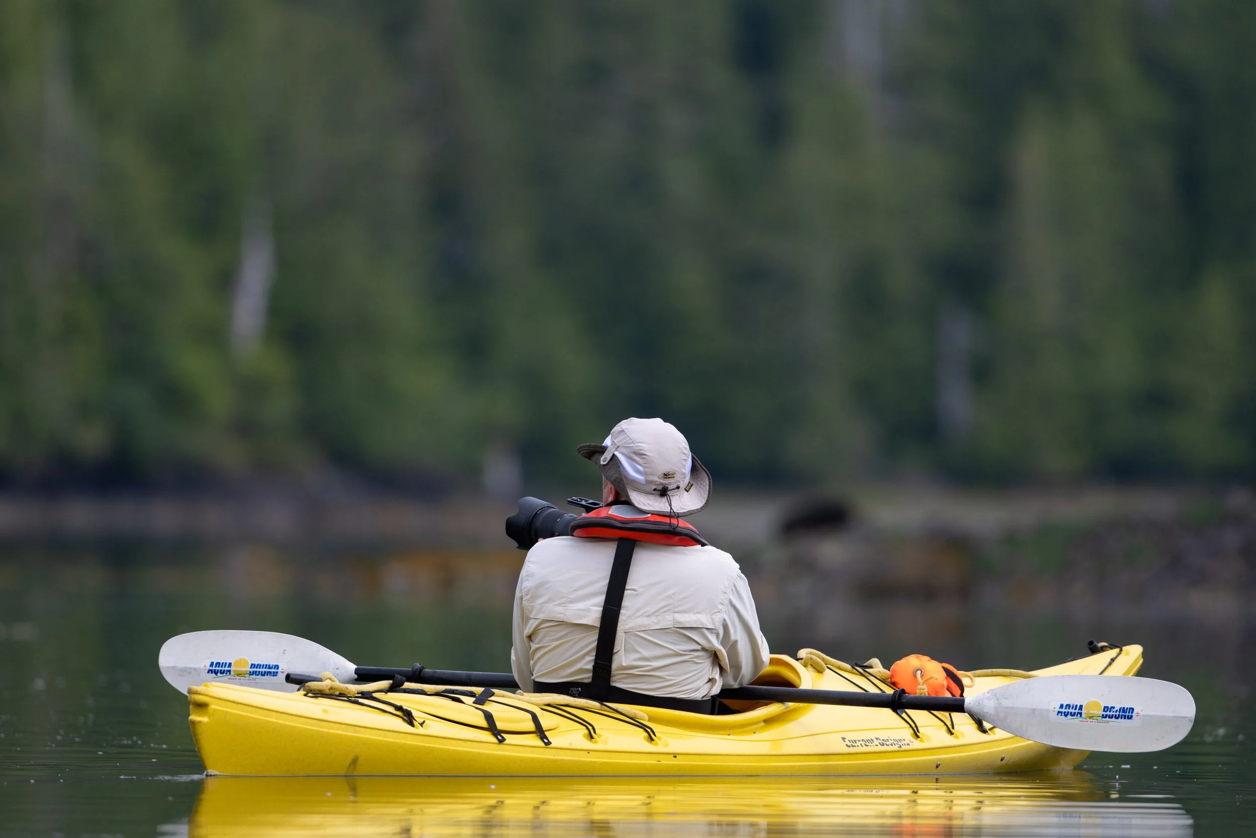 A photographer balancing in a kayak while making images