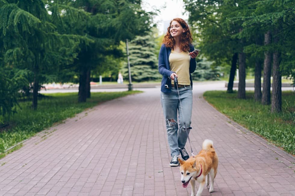 smiling-woman-walking-dog-at-park