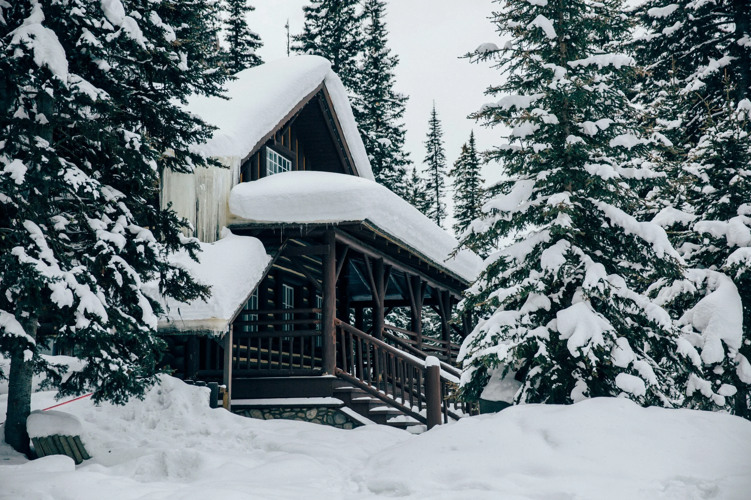 Large log cabin in the forest under deep snow