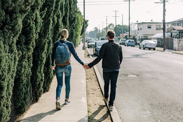 man-holding-woman-while-walking-on-sidewalk