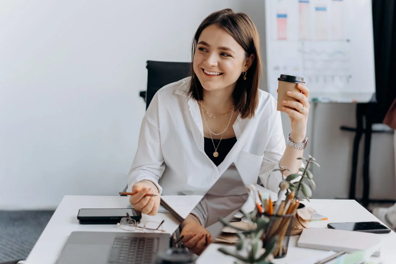 a-happy-woman-sitting-on-the-swivel-chair-while-holding-a-cup-of-coffee