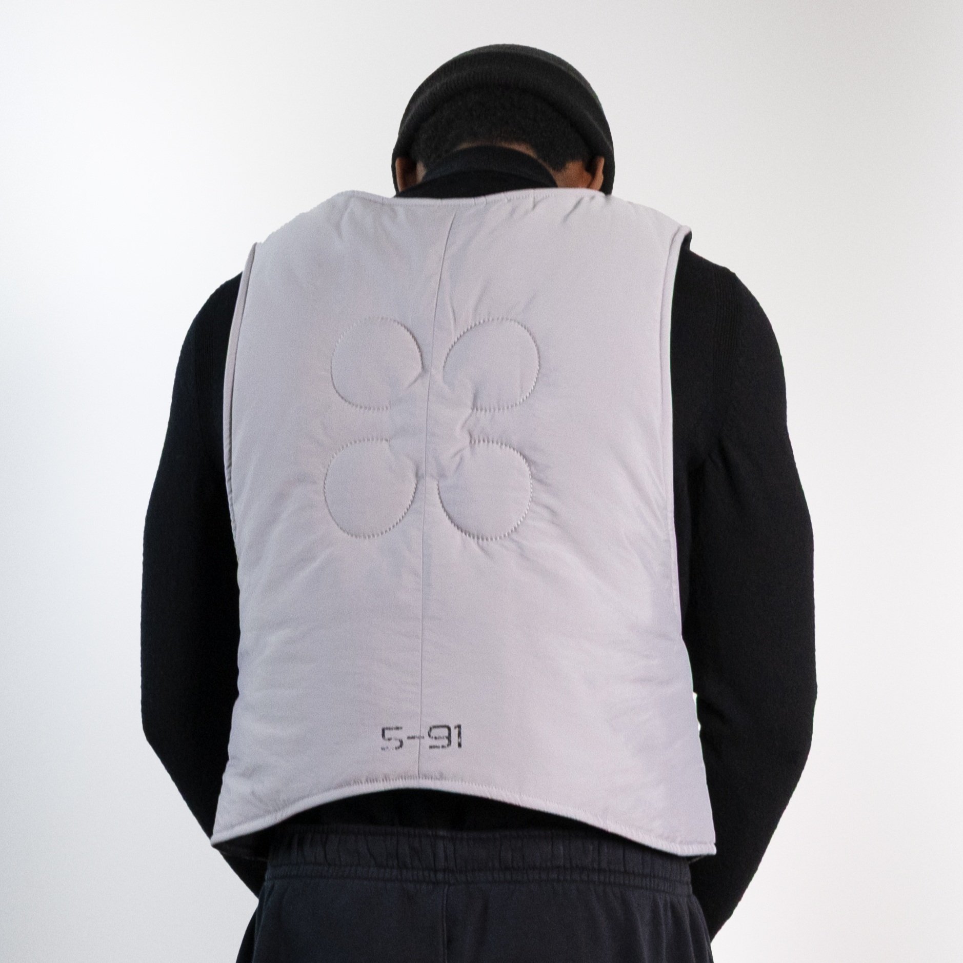 Grey puffer vest with assymetric curve flap closure, overlapping vest, asymmetric vest, asymmetric puffer vest