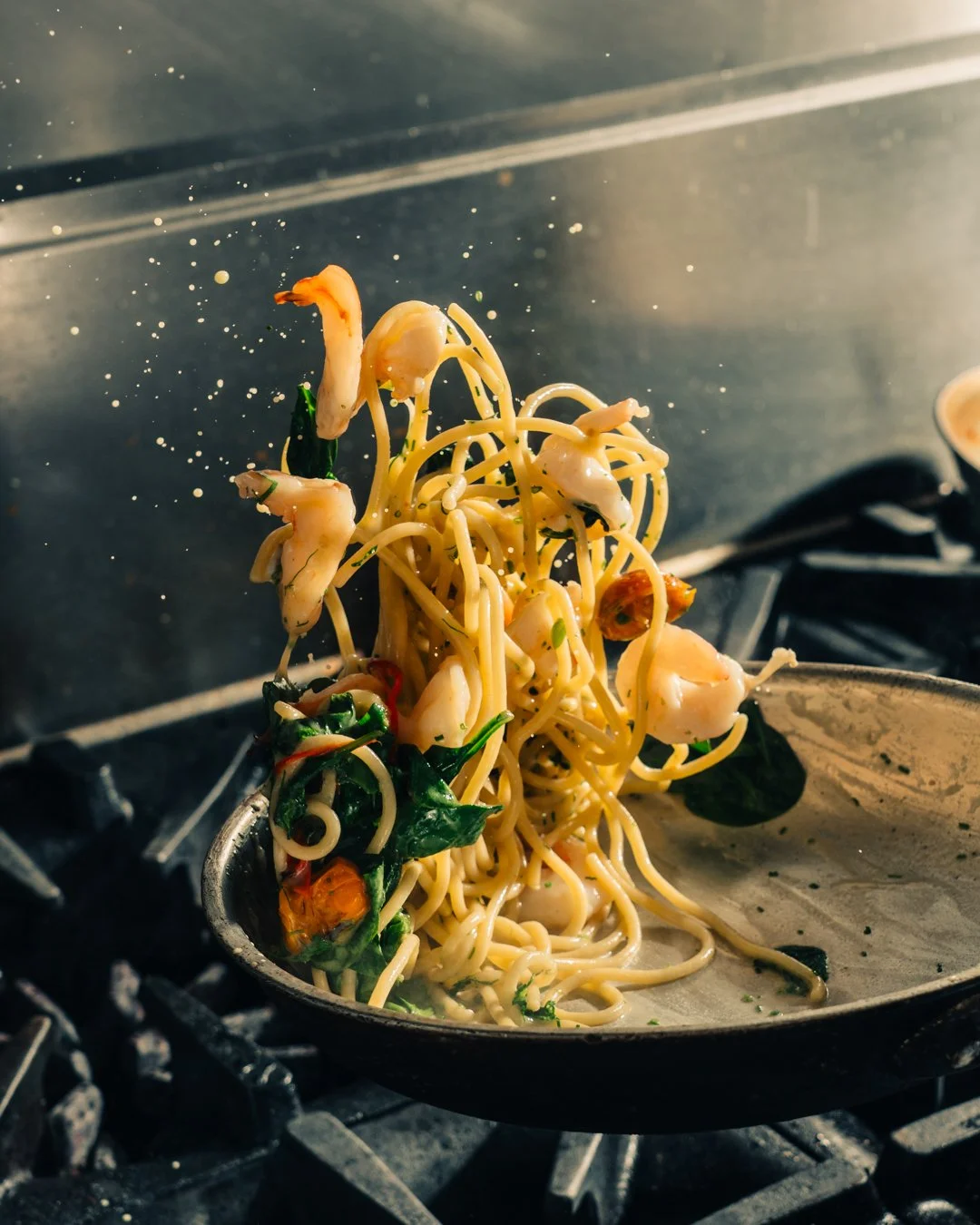 Seafood pasta being tossed in a frying pan over a stove.