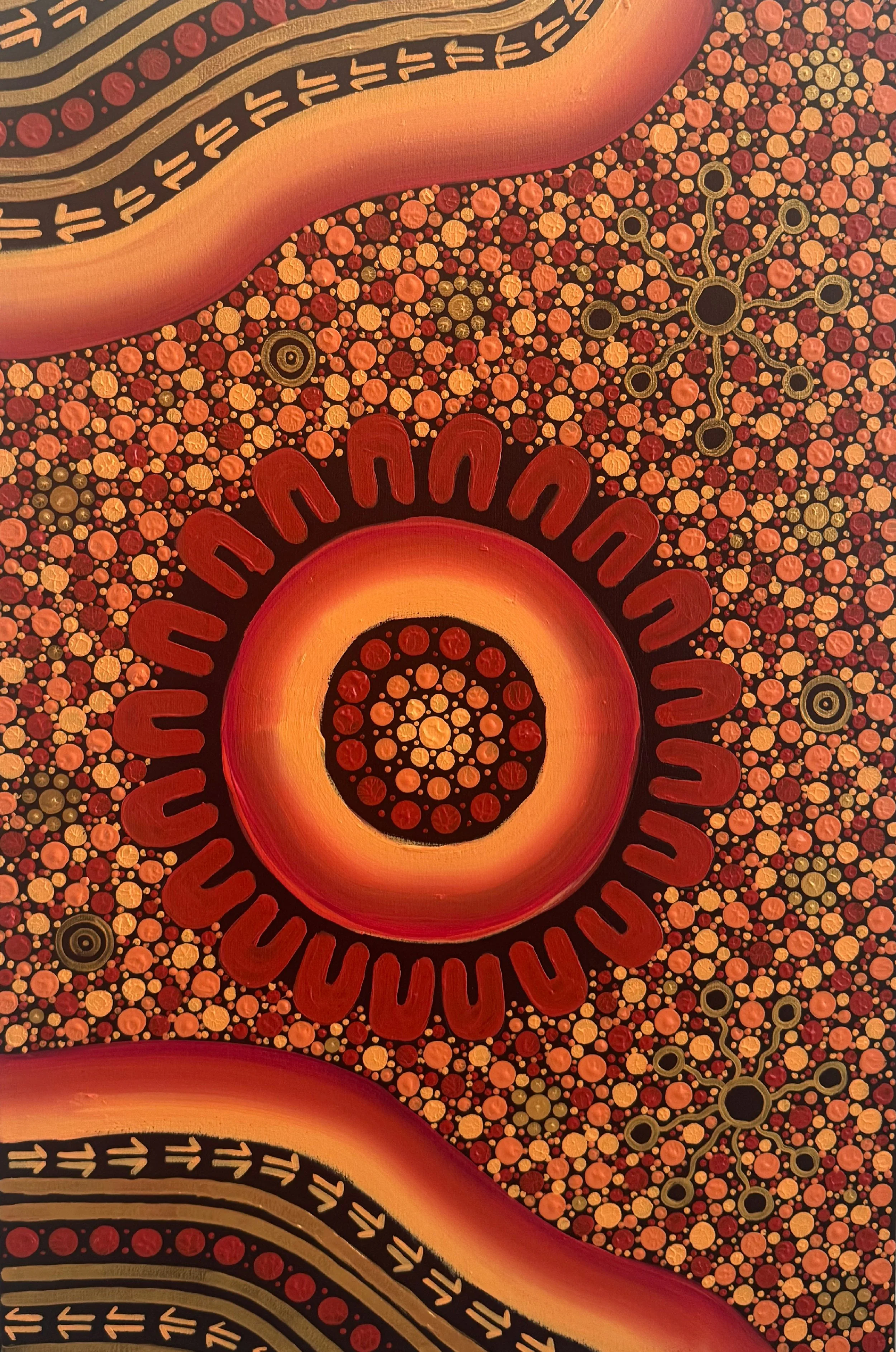 Close-up of Aboriginal-style dot painting with concentric circles, wavy patterns, and interconnected shapes in warm colors like orange, red, yellow, and black.