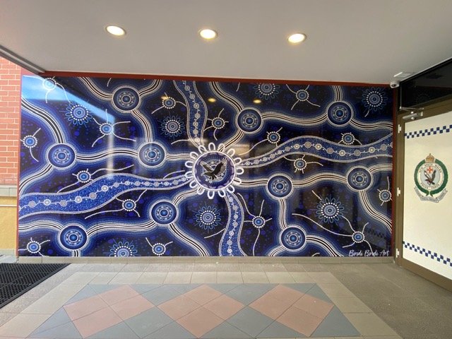 Colorful wall mural featuring a circular design with a bird and abstract patterns in blue, white, and gold.