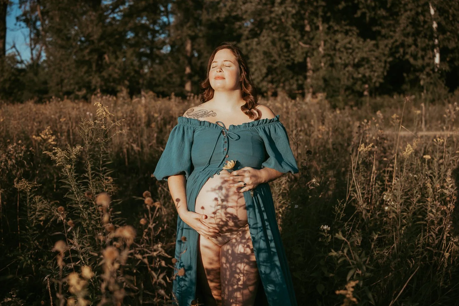 woman standing in the setting sun during her maternity session with AMG Photography