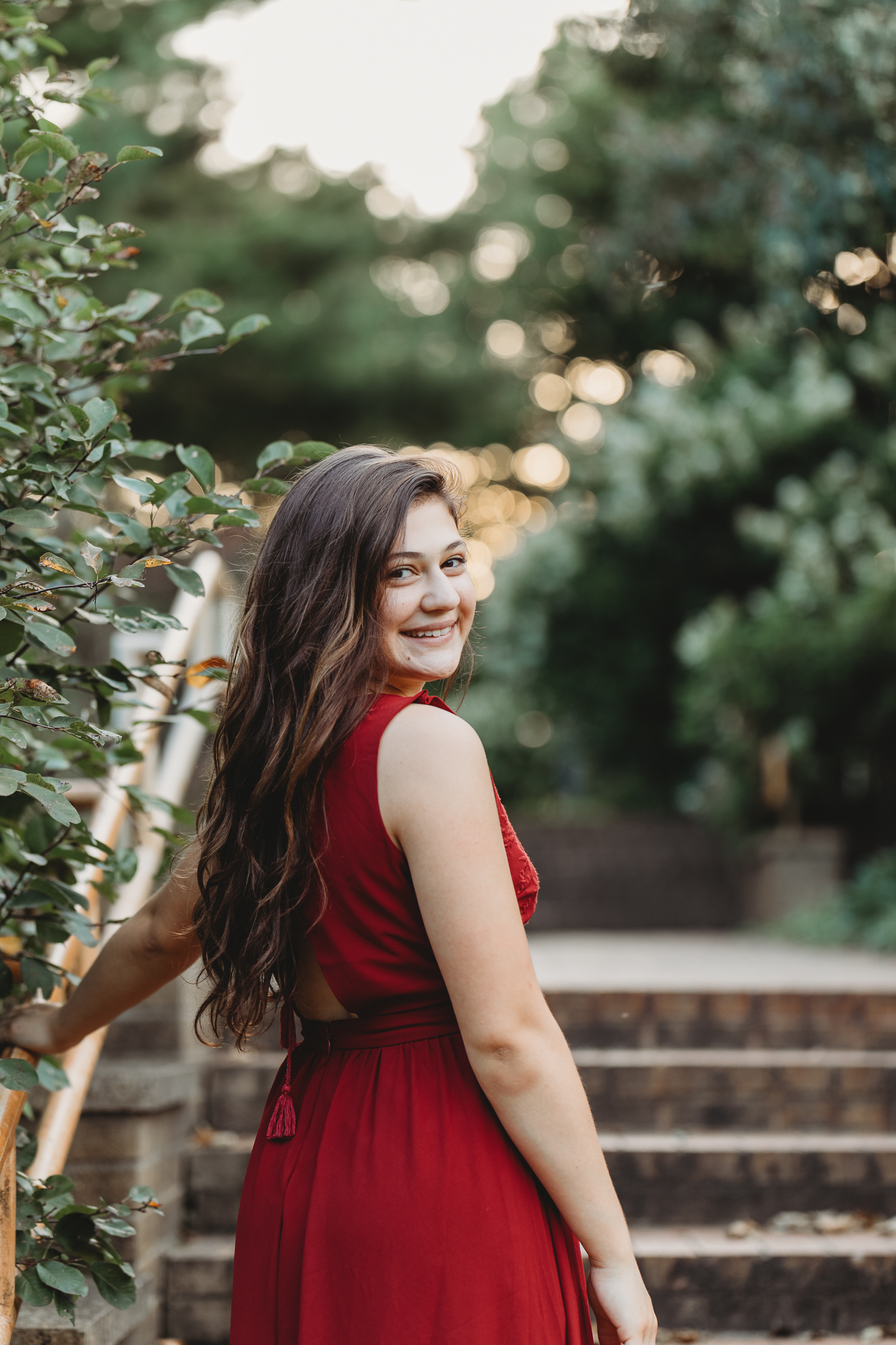 A high school senior in a long red dress walking up a stairway | AMG Photography