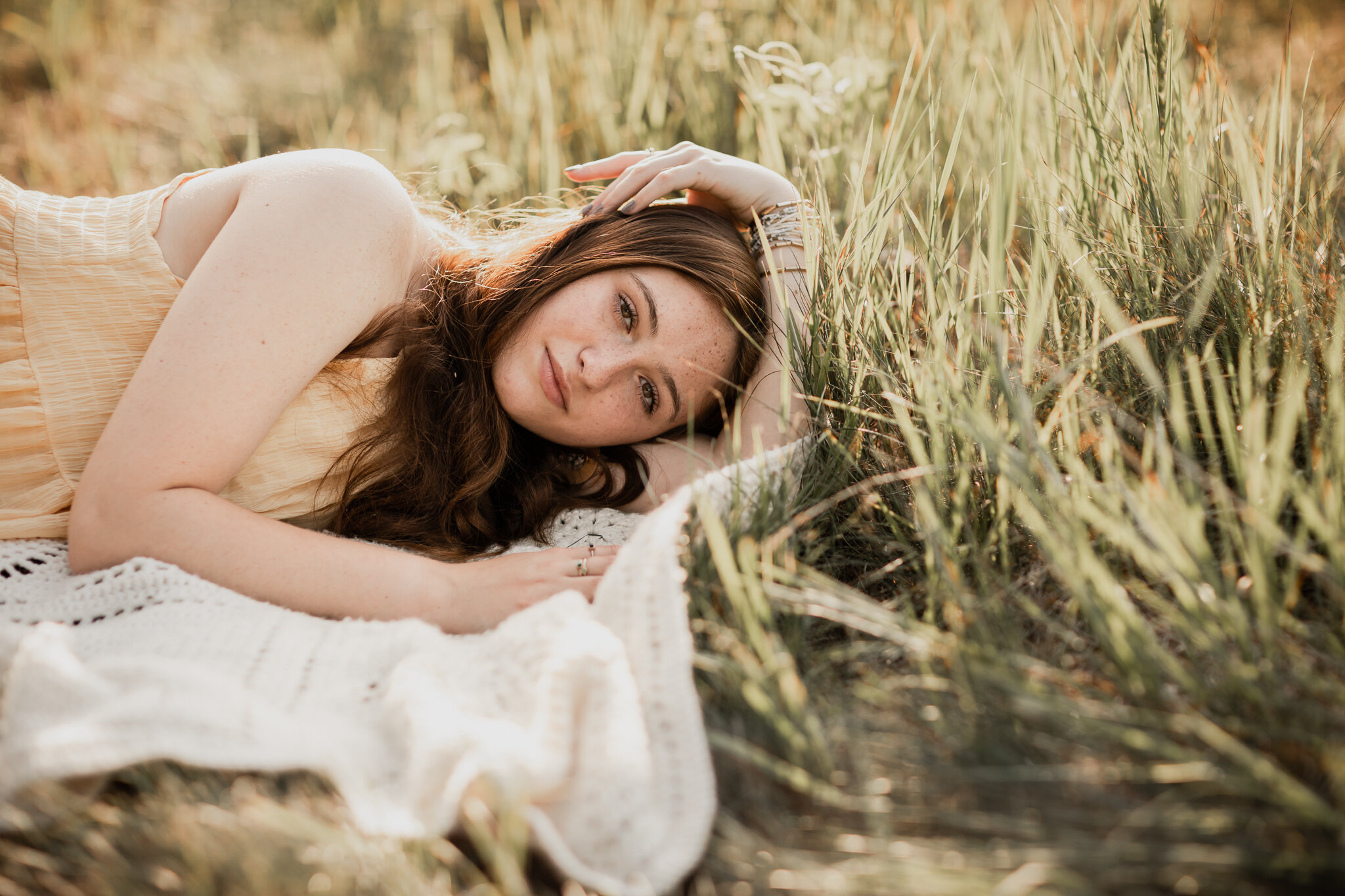 A teen girl lying on a blanket in a field at Hansen Tree Farm in Anoka, Minnesota | Minnesota Senior Portrait Photographer