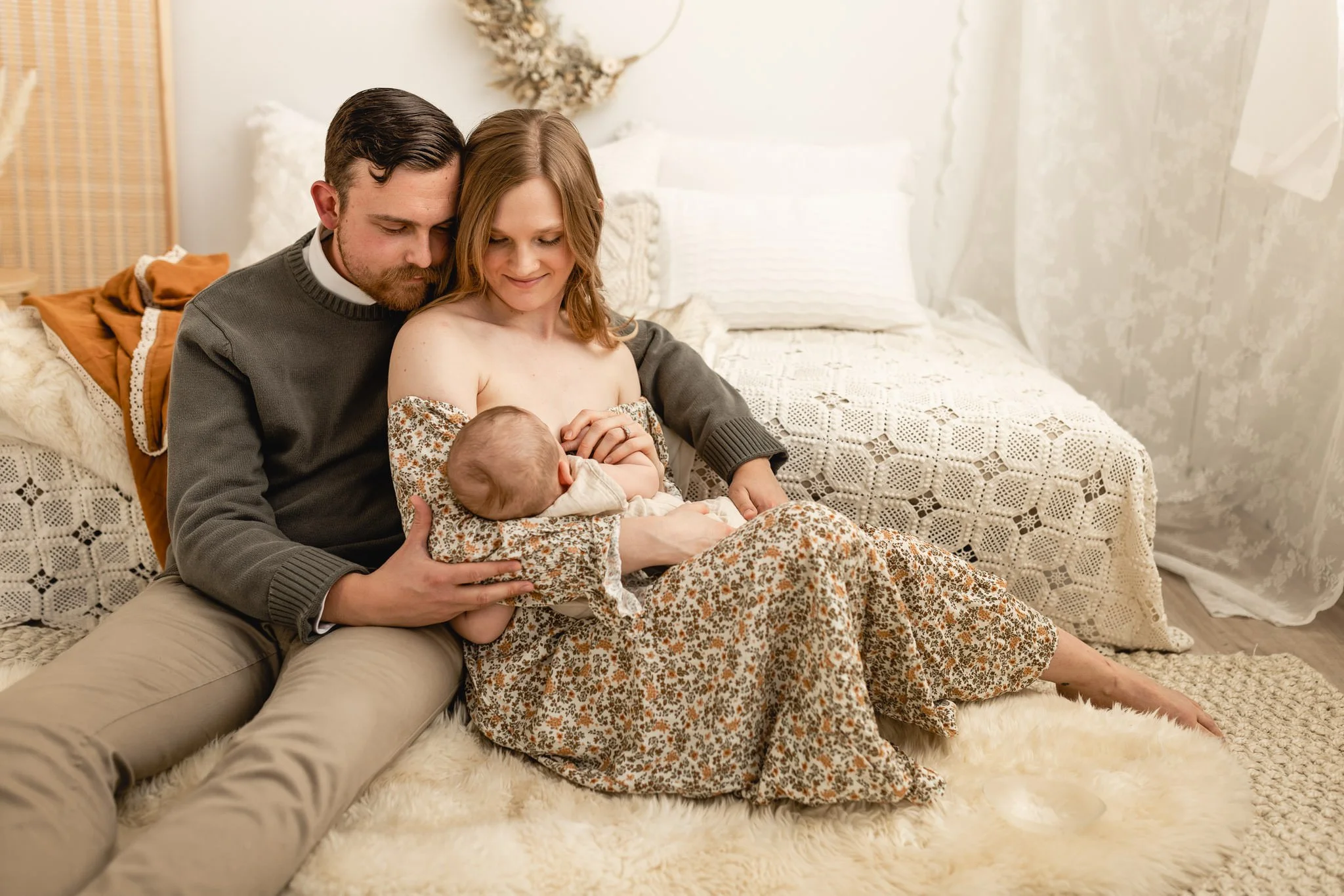 a mom and dad are sitting next to each other on the floor during a newborn session with Ann Marie from AMG Photography