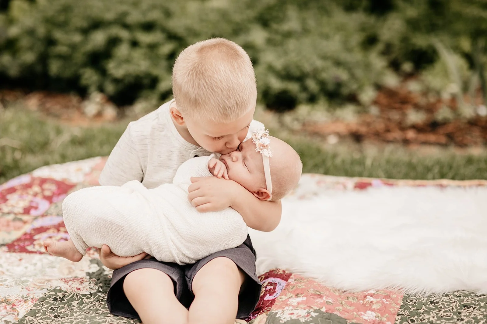a big brother is kissing his new baby sister