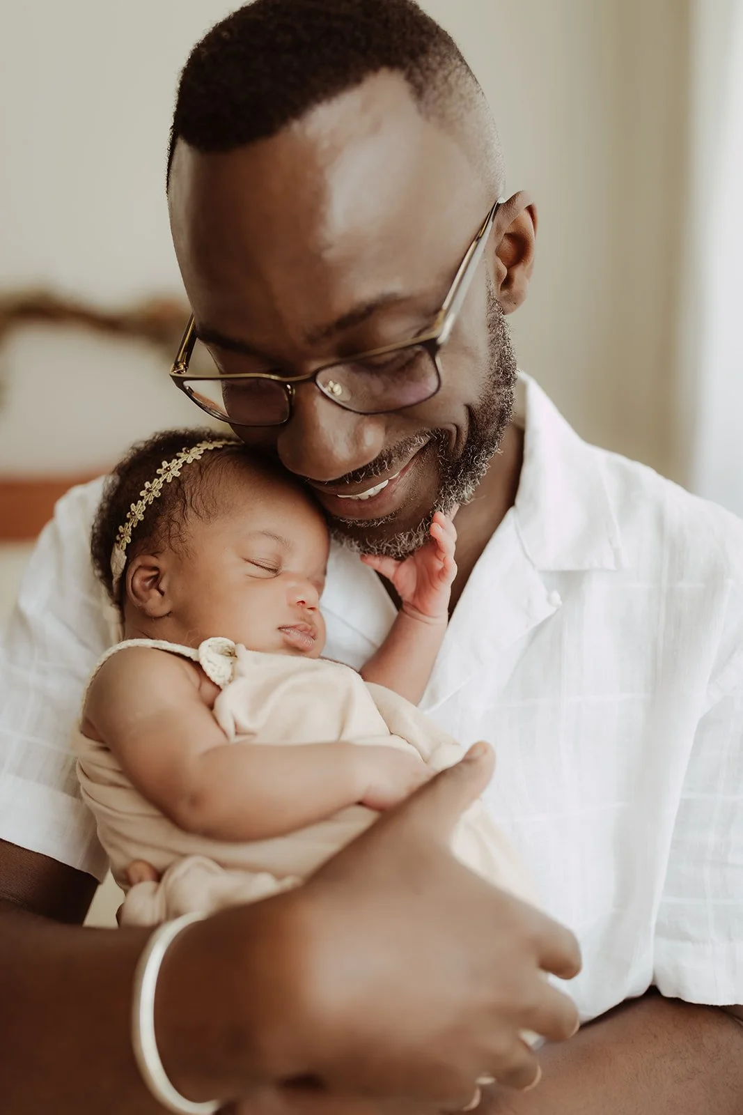 A father holds his baby girl on his chest and smiles during their Minneapolis newborn photography session. 