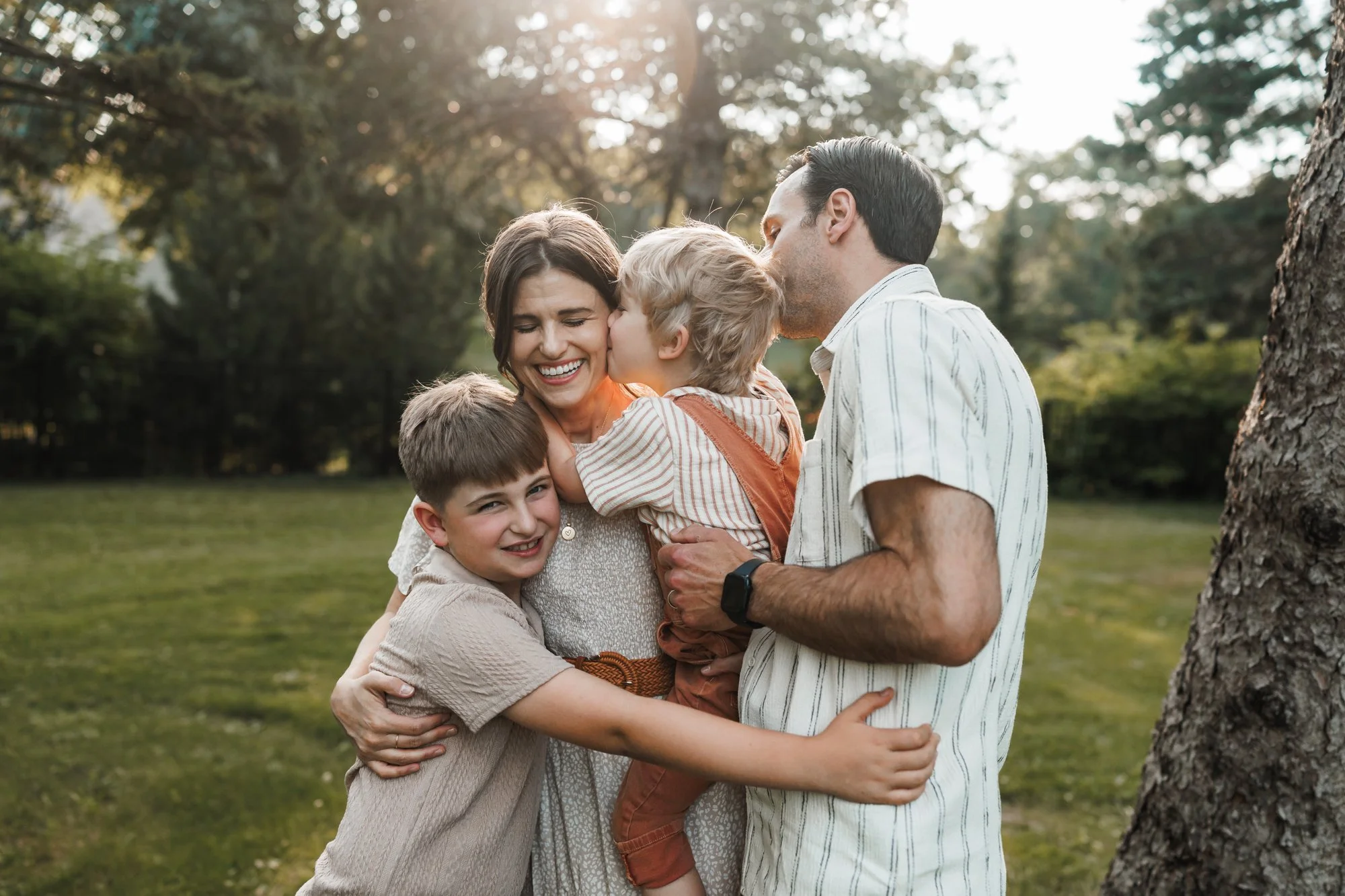 family of four is hugging each other during a family photo session at Arneson Acres Park in Edina, MN