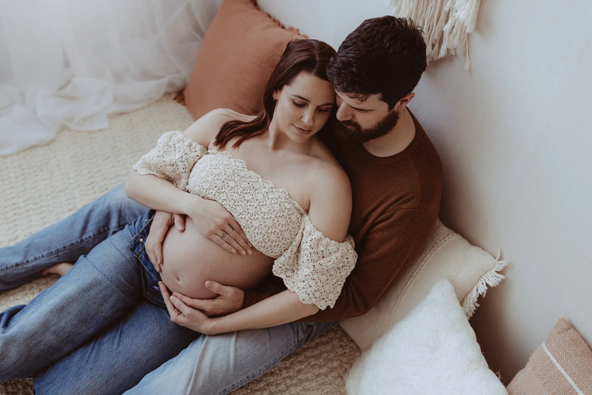 pregnant woman is sitting on the floor with her husband