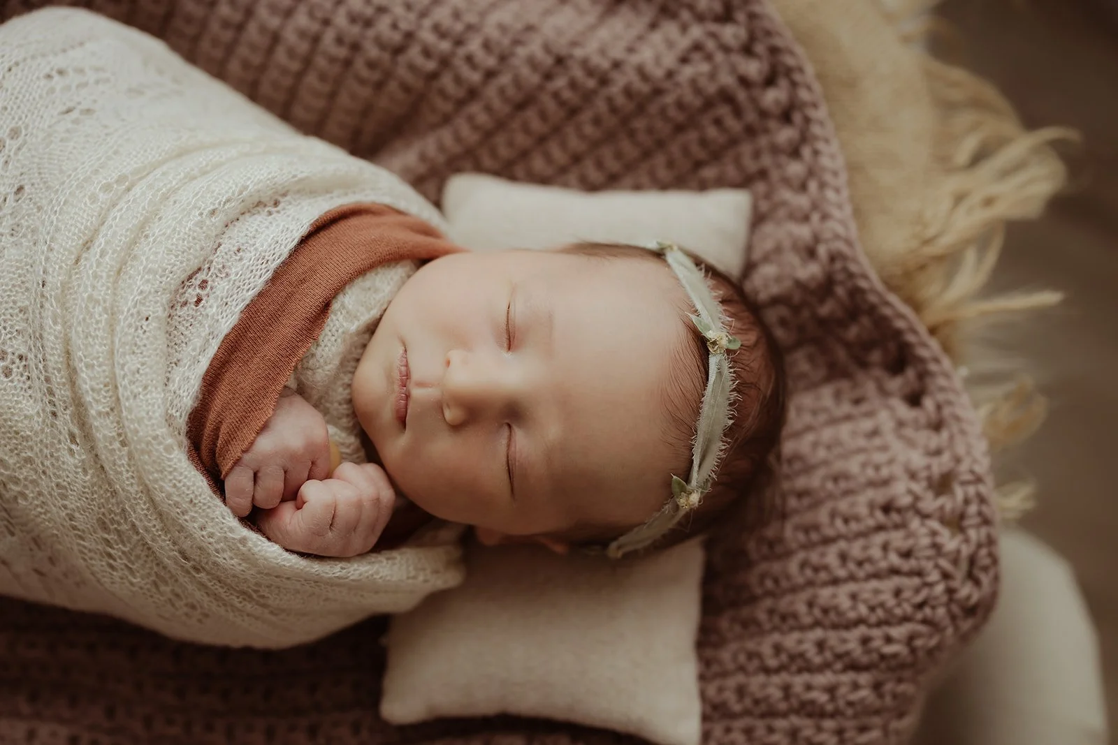 baby girl is swaddled and sleeping in a basket