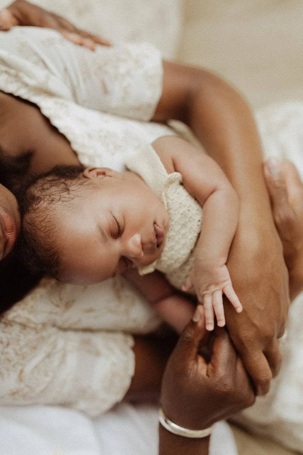 A baby girl sleeps soundly on her mother's chest.
