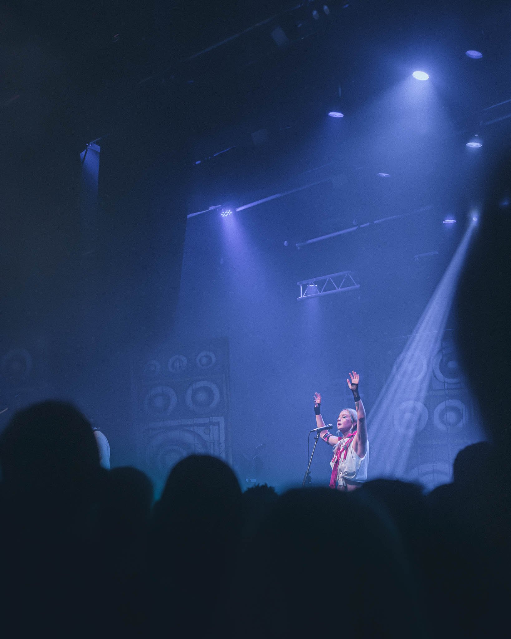 Dead Pony supporting Skindred at KK's Steel Mill, Wolverhampton. A female singer performing on stage with her hands raised, surrounded by blue stage lights and sound equipment, during a concert.