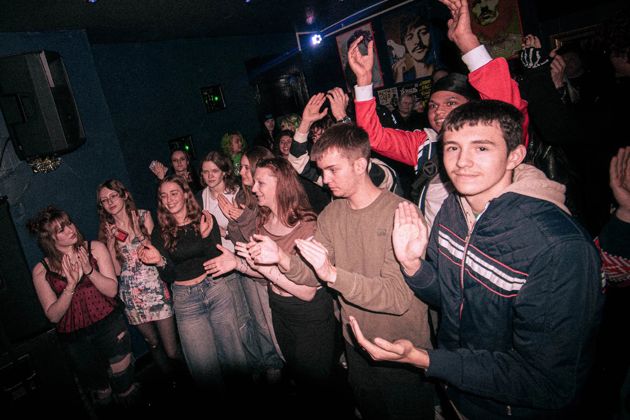 Crowd enjoying a show at Dive, Wolverhampton. Group of young people dancing and enjoying music at a party or club with colorful lighting and artwork on the wall.