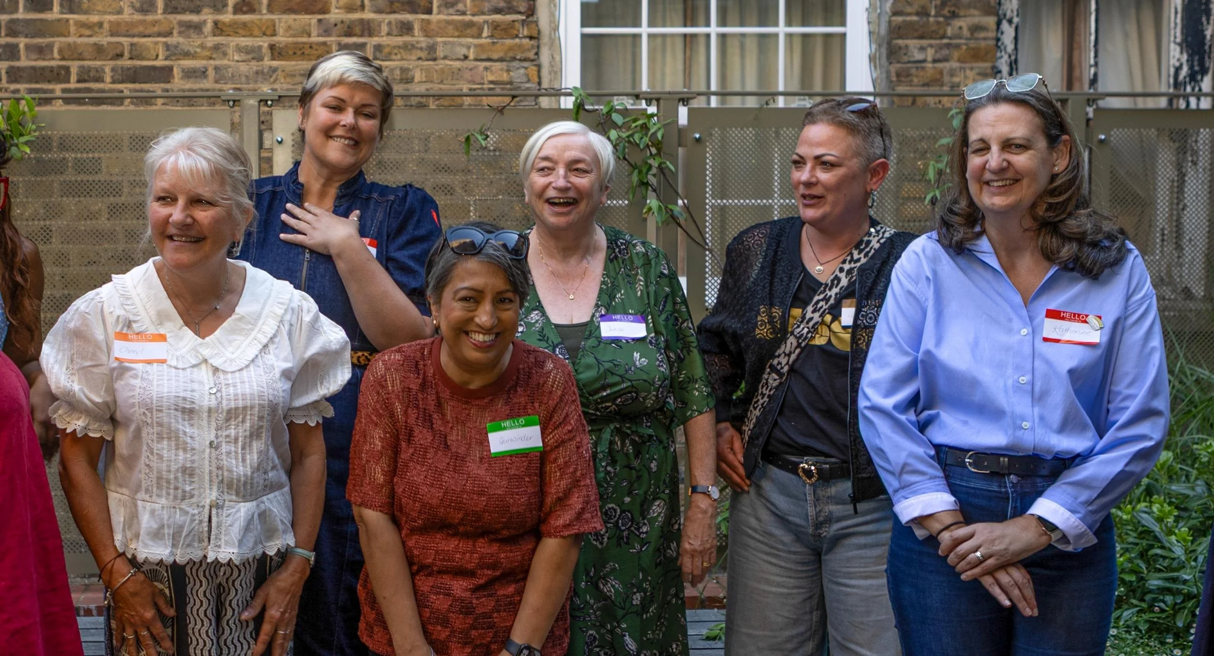 A group of 6 laughing women who have TNBC, meeting and chatting together at a UK Charity for TNBC event.