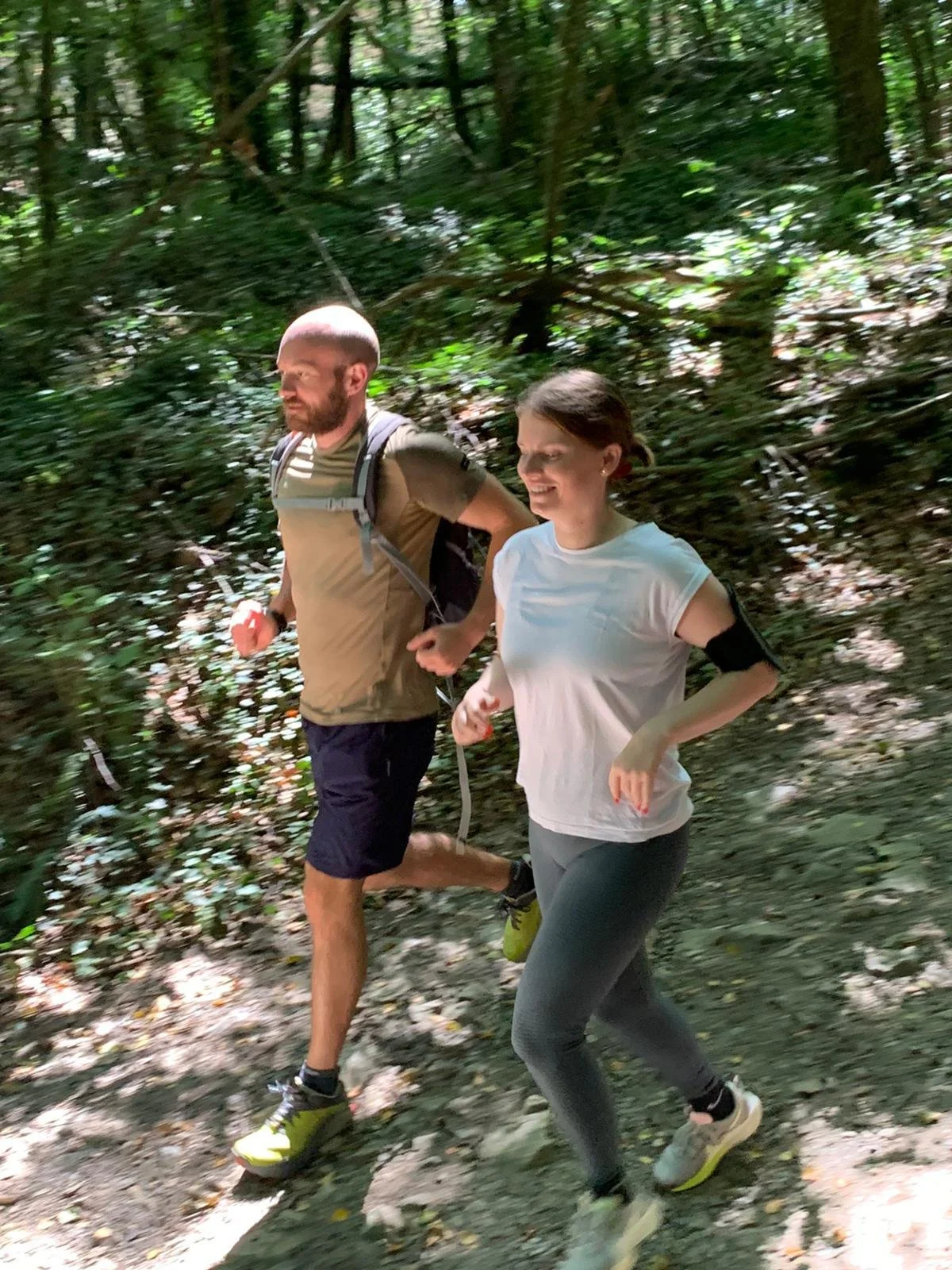 Coach sportif accompagnant une femme lors d’un footing en forêt pour améliorer énergie, récupération et santé globale