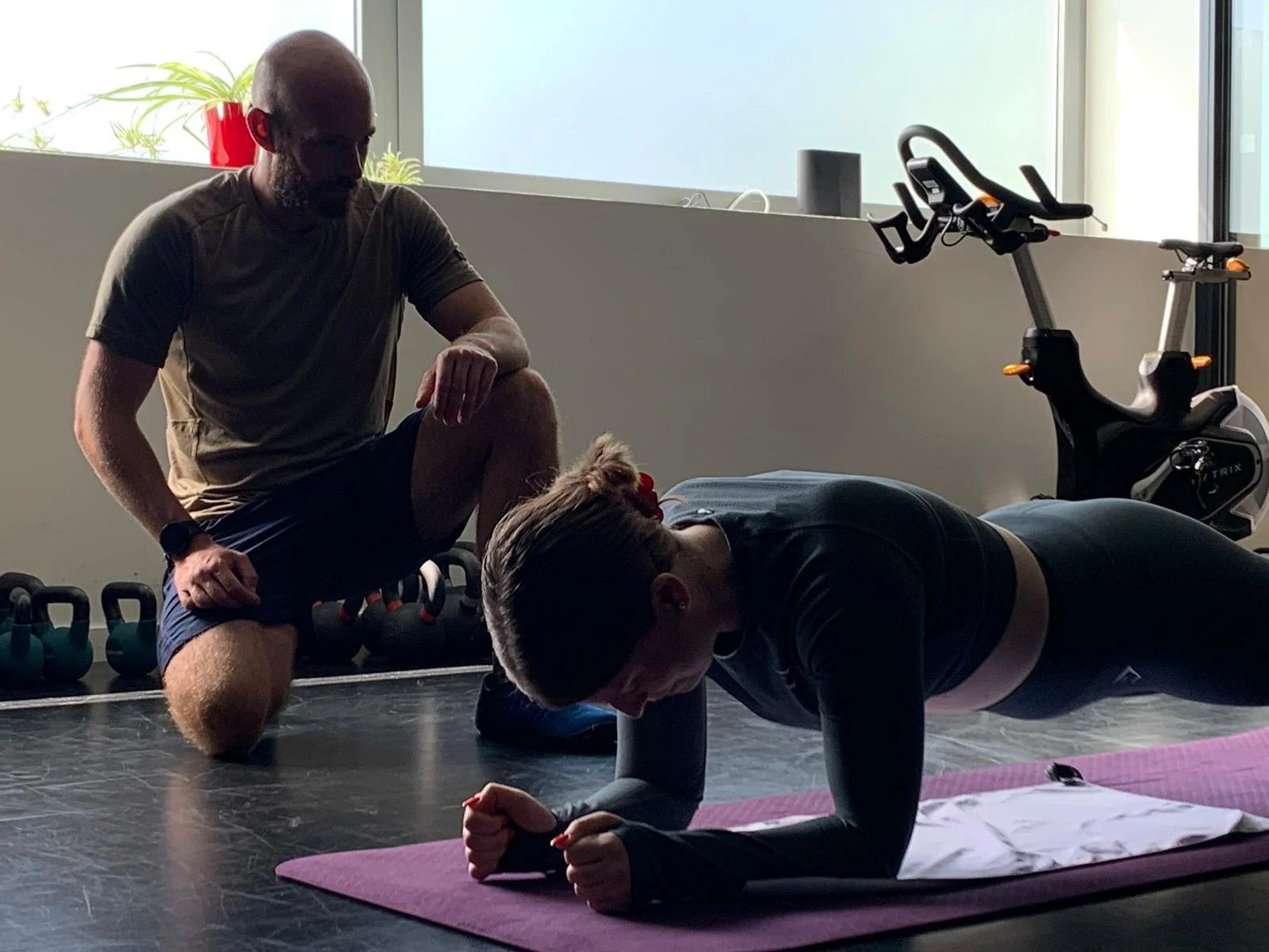 Coach sportif supervisant un exercice de gainage afin de renforcer la base et prévenir les blessures dans une préparation sportive