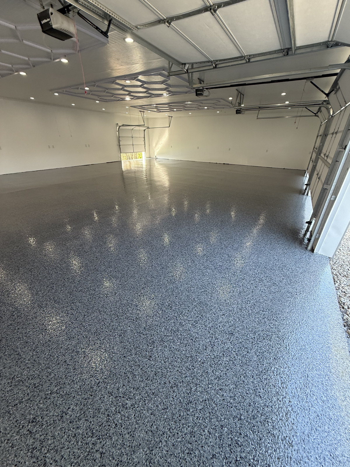 Close-up of a speckled black and white terrazzo flooring next to a plain beige floor in an indoor space.