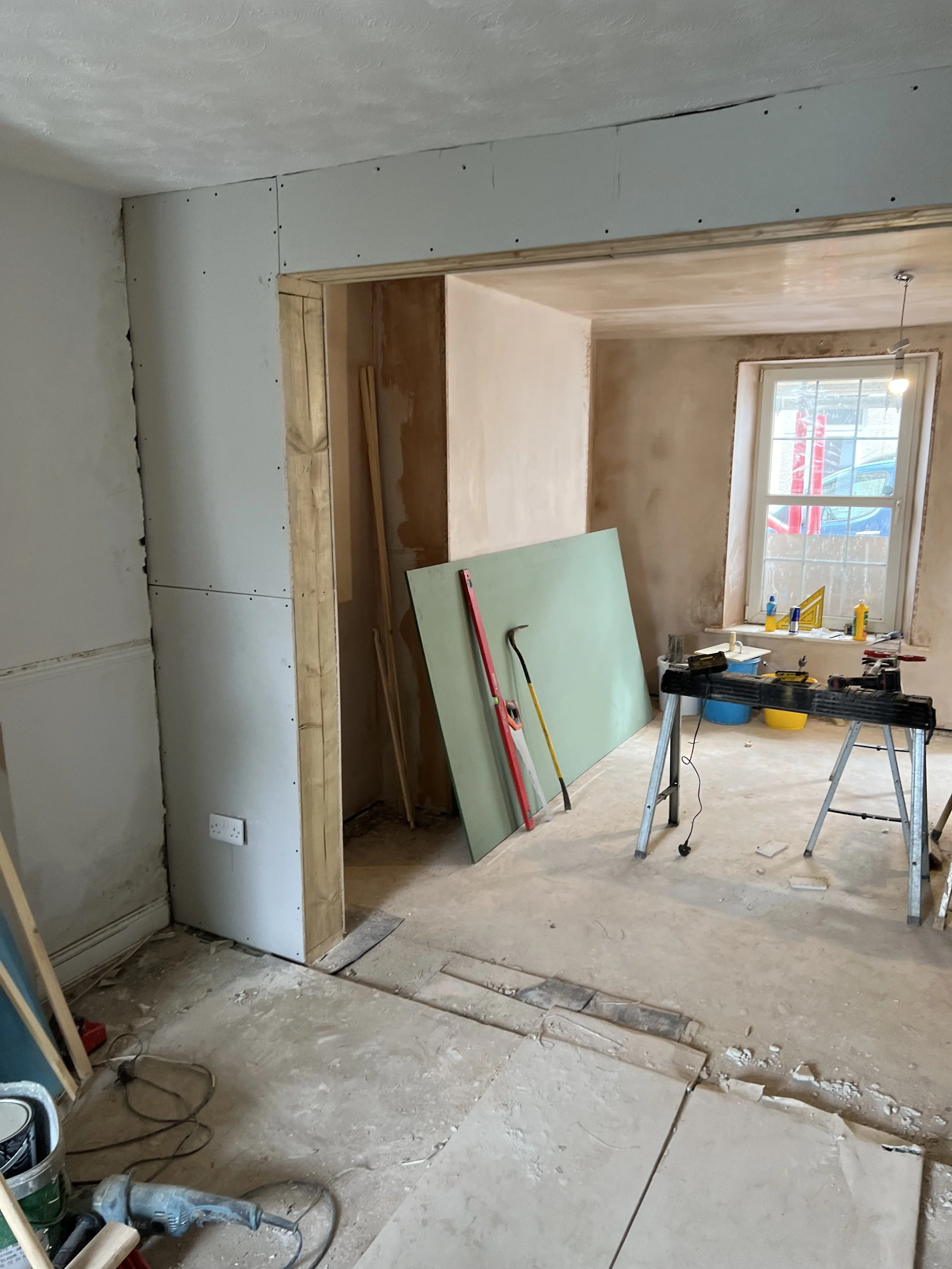 Interior room under renovation with construction tools, drywall, and unfinished walls.