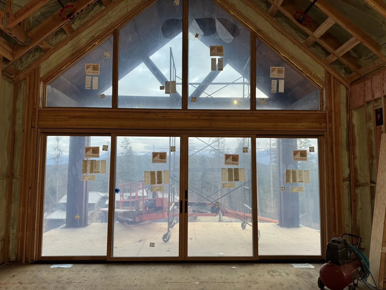 A new build in the mountains outside of Bigfork, Montana, with large wooden framed windows.