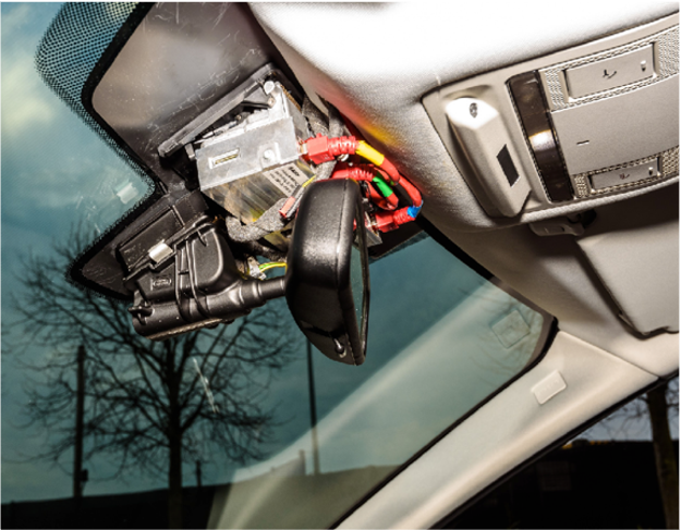 A car rear view mirror with sensor and camera components displayed showing internal digital workings of a vehicle.