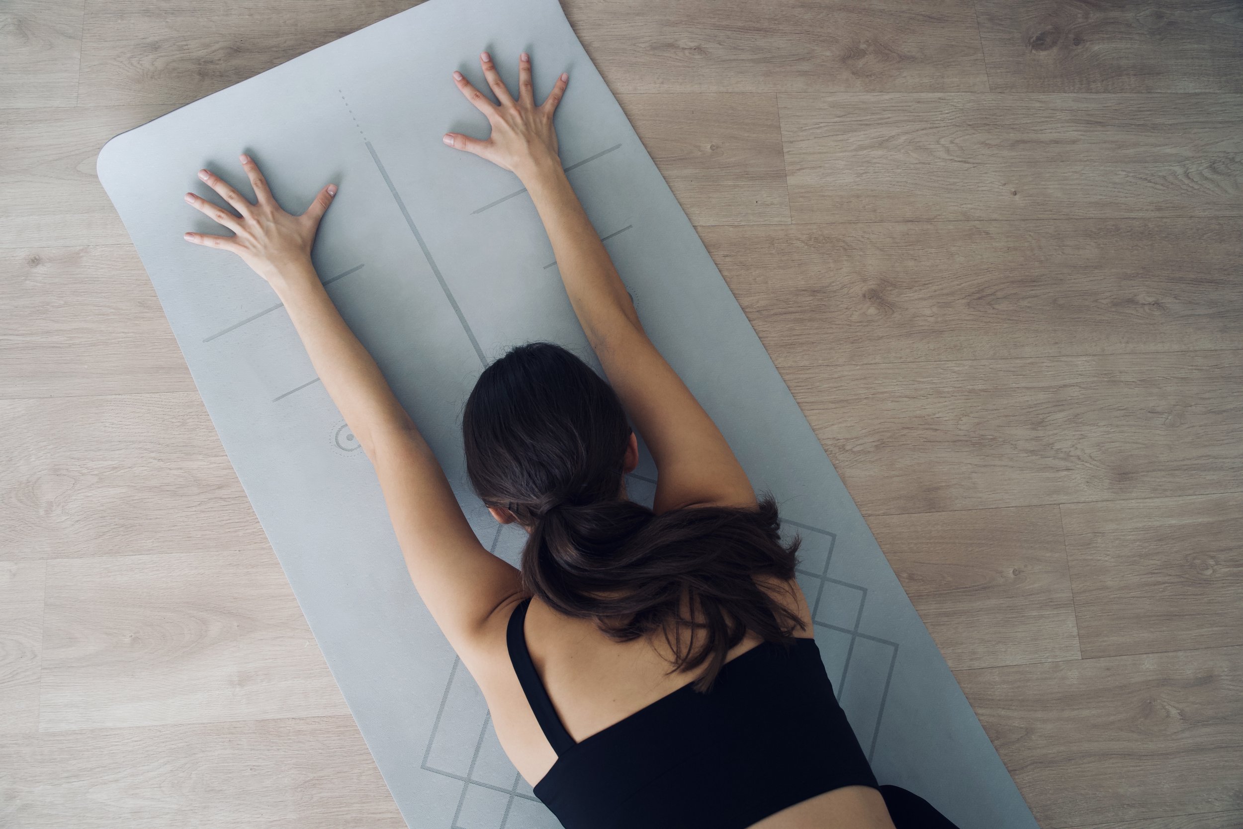 Overhead view of hands stretched on a yoga mat during a studio yoga class