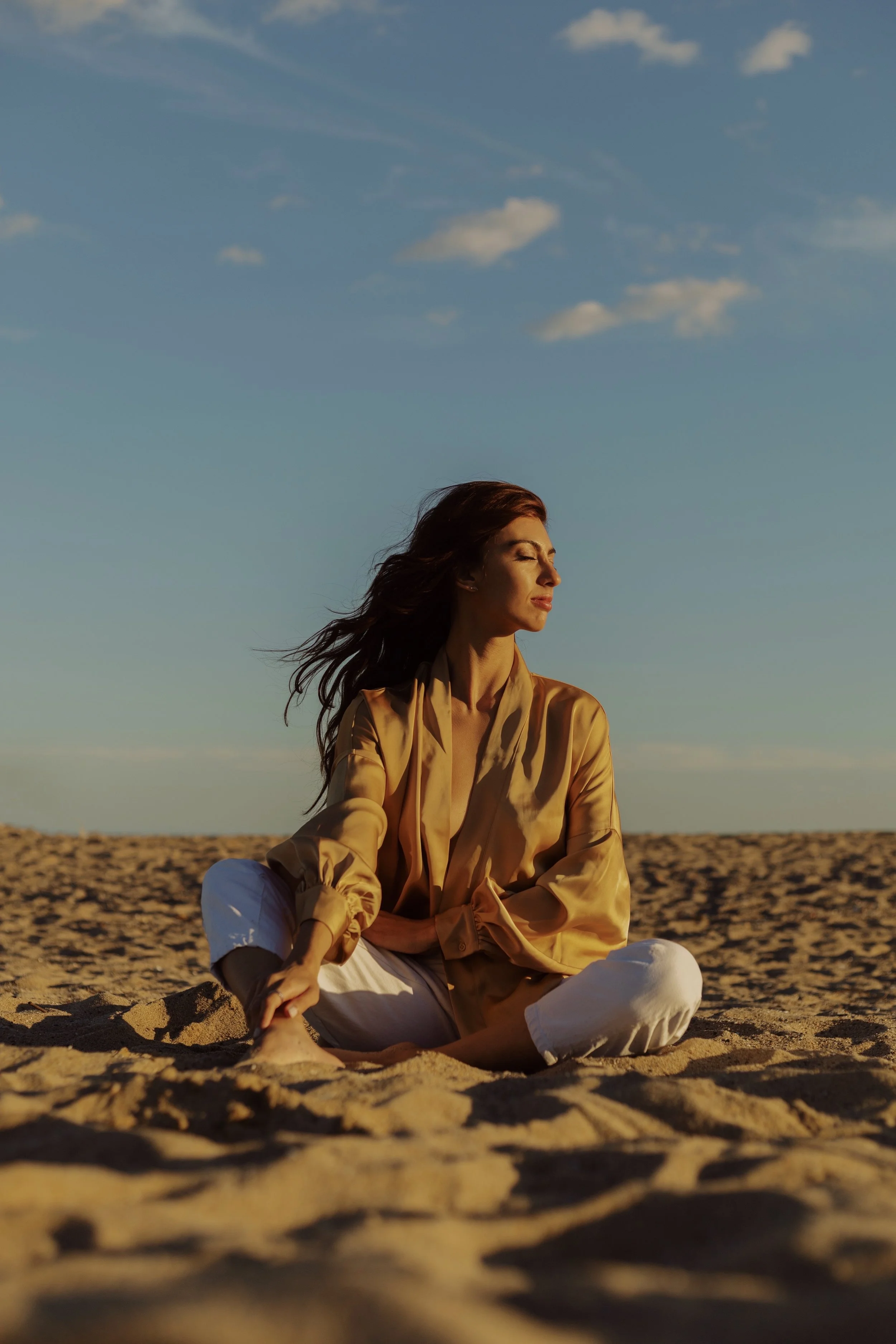 A person smiling warmly, standing on a sandy beach with a vast, open sky in the background, symbolizing joy, connection to nature, and the infinite possibilities of the cosmos.