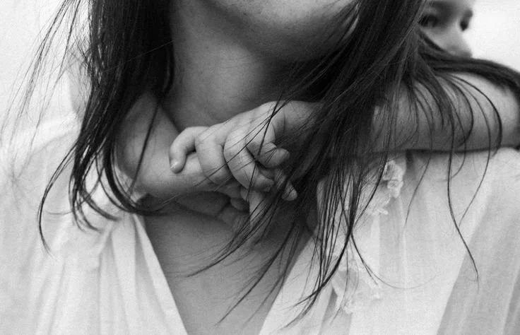 Black and white photo of a child hugging their mother, symbolizing ancestral connection and feminine lineage healing