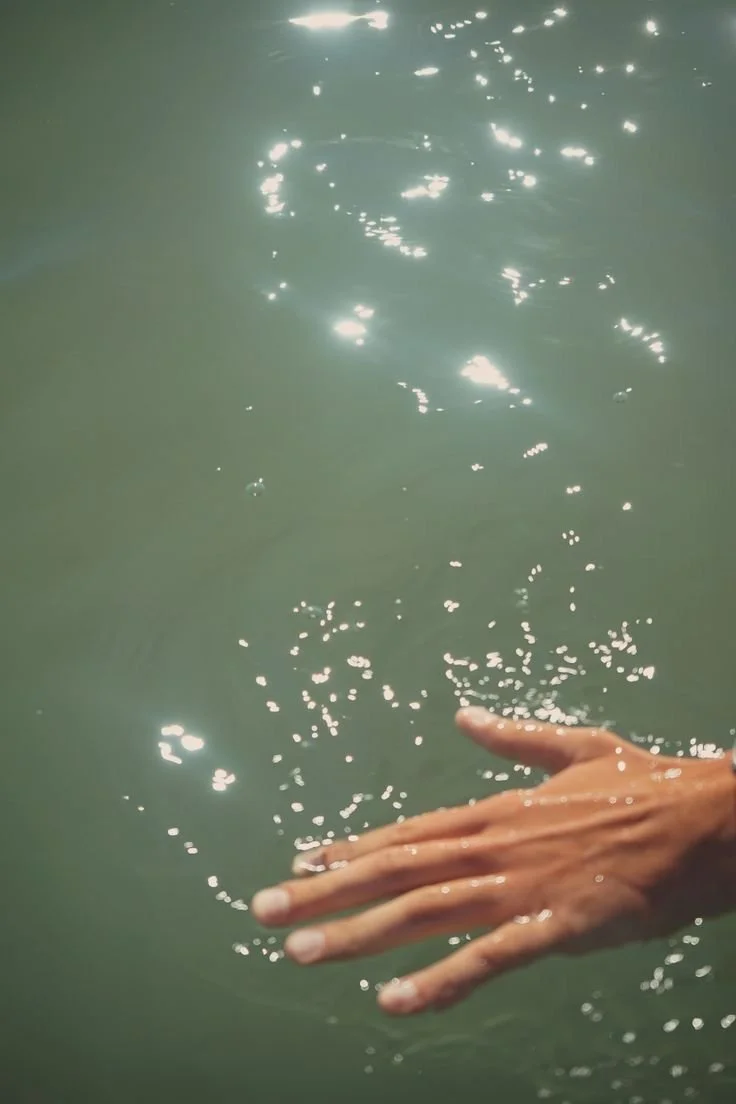 Hand gently touching water, representing the fluid, intuitive energy of the feminine and ancestral connection through the motherline