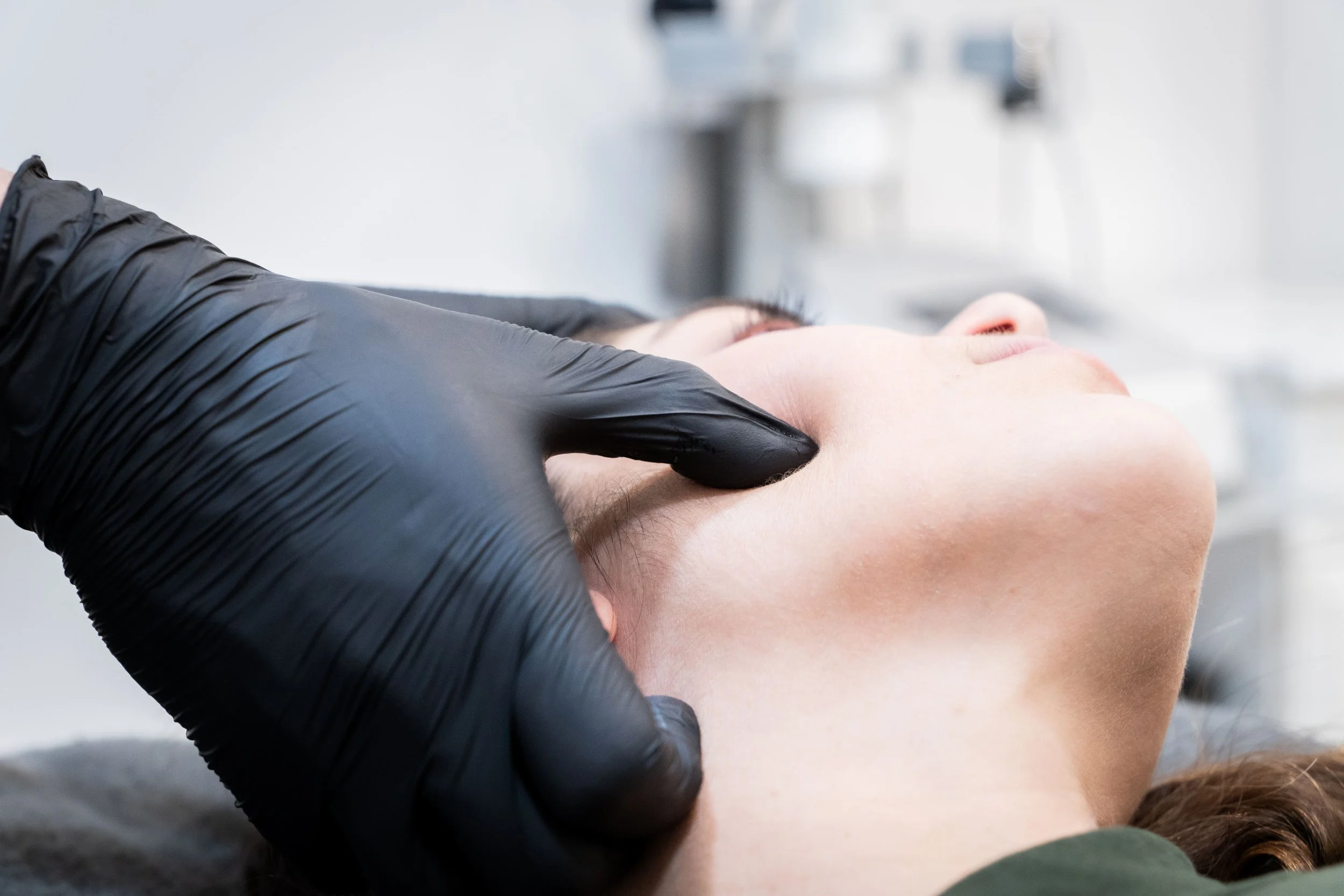 persona con guantes negros recibiendo terapia o masaje en la cara