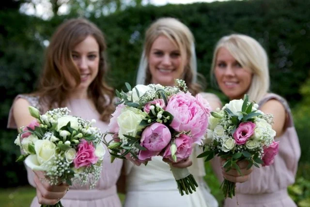 Bride and bridesmaids holding three bouquets