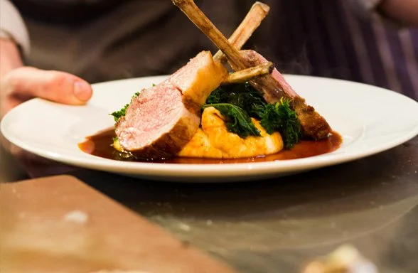 Chef holding a plate of two chops, artfully arranged