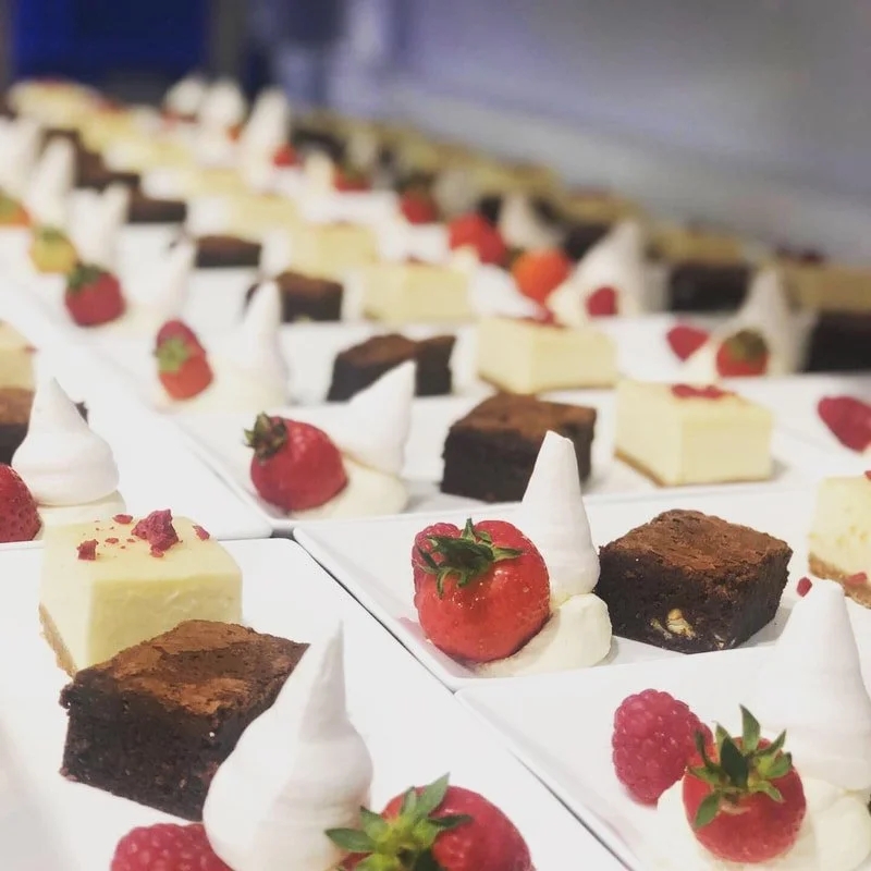Rows of dishes containing brownies, strawberries and meringue