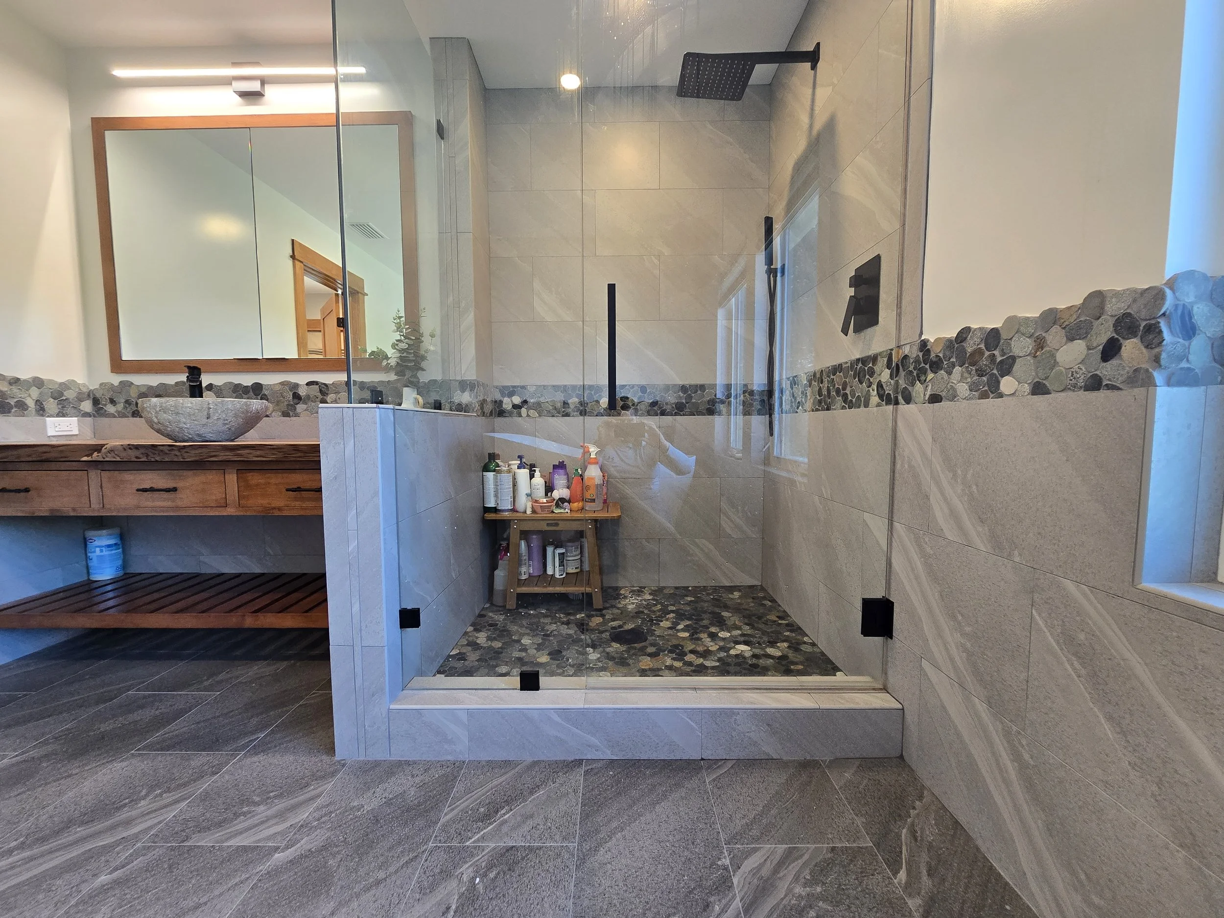 Walk-in shower with pebble mosaic floor and accent band, large-format wall tile and frameless glass, Napa