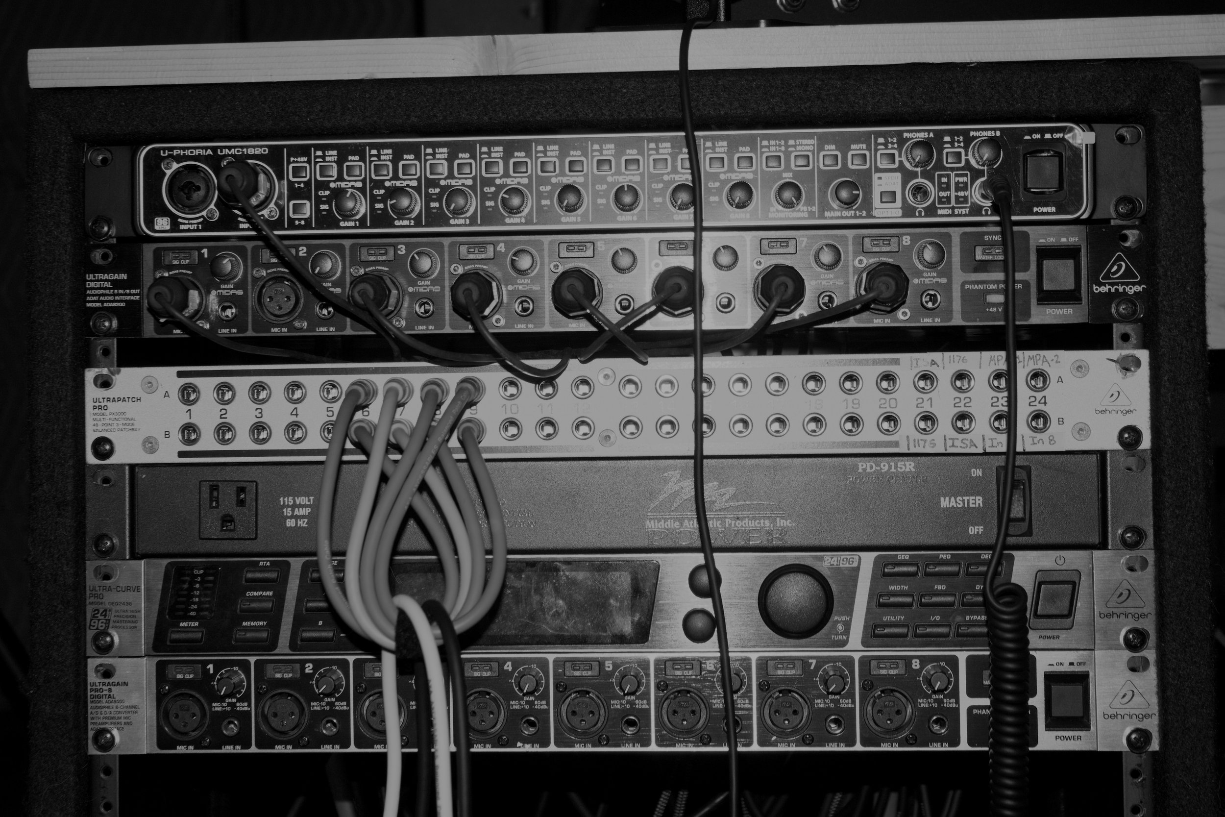 A rack full of audio recording gear, including an audio interface, preamps, and a patchbay.