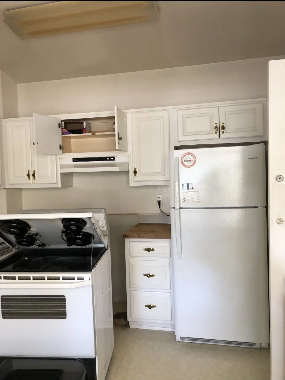 Tight appliance wall with dated range and fridge cutting into the workspace.