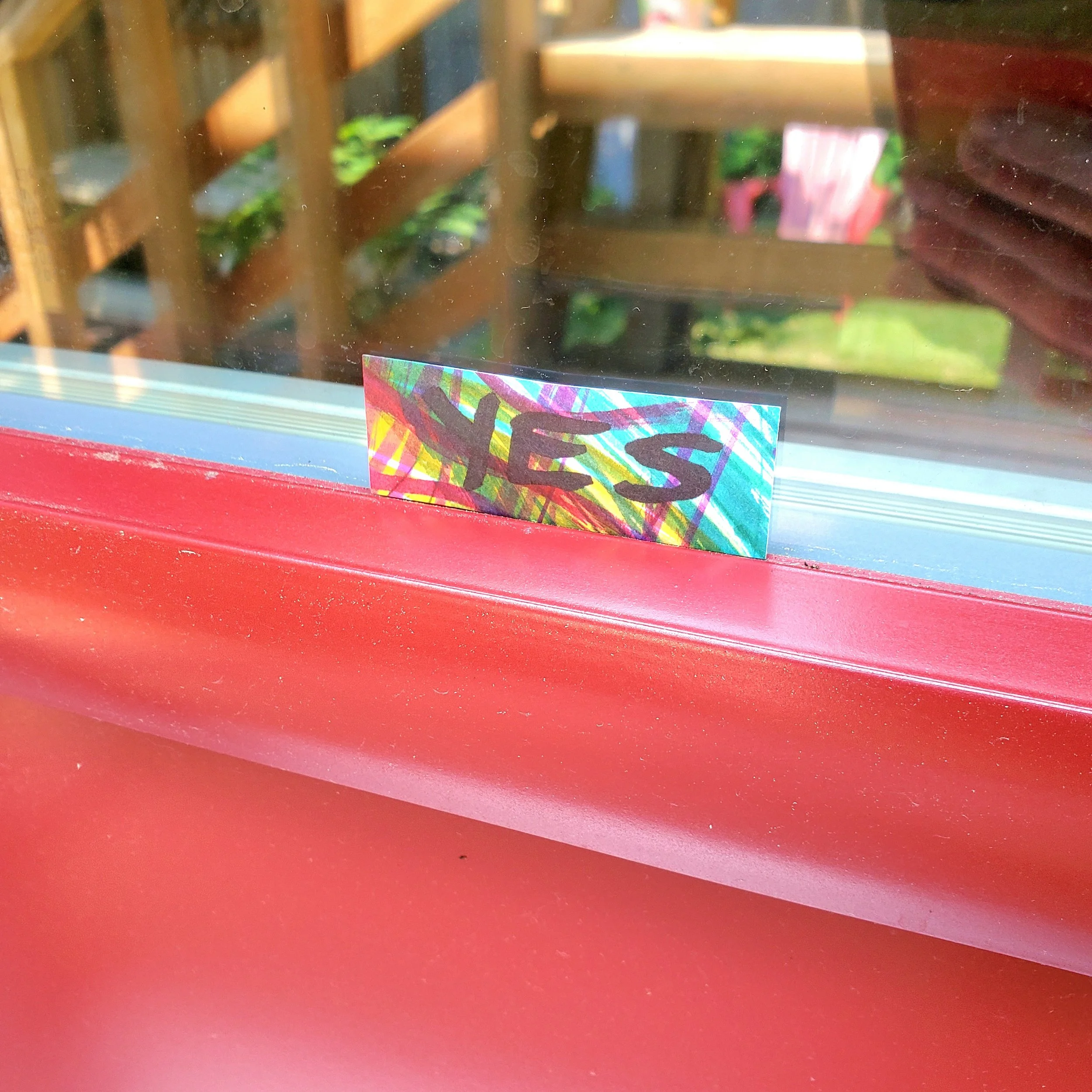 The word yes printed on a little card, placed on the window sill of the red door to my office.