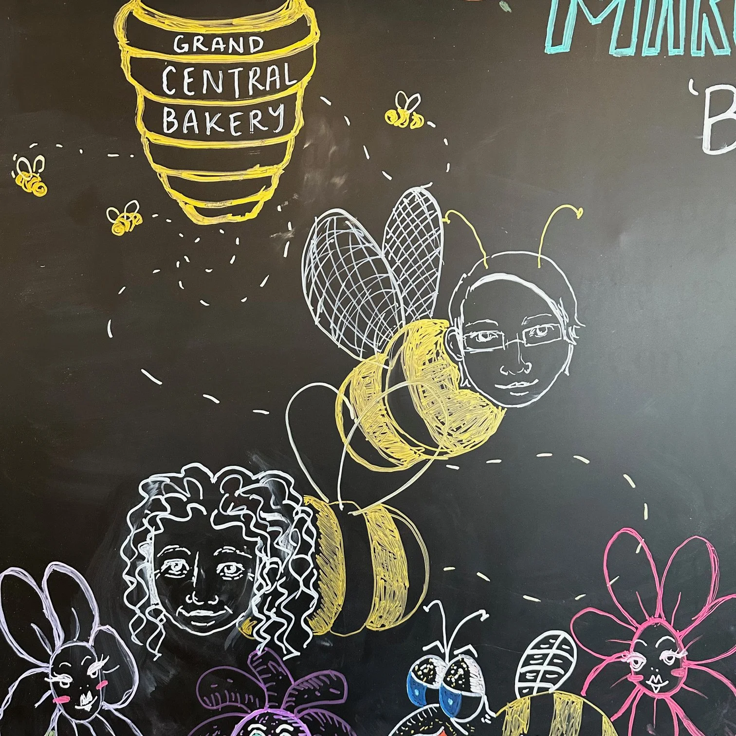 Chalkboard art, featuring a beehive, flowers, and bees with human faces.