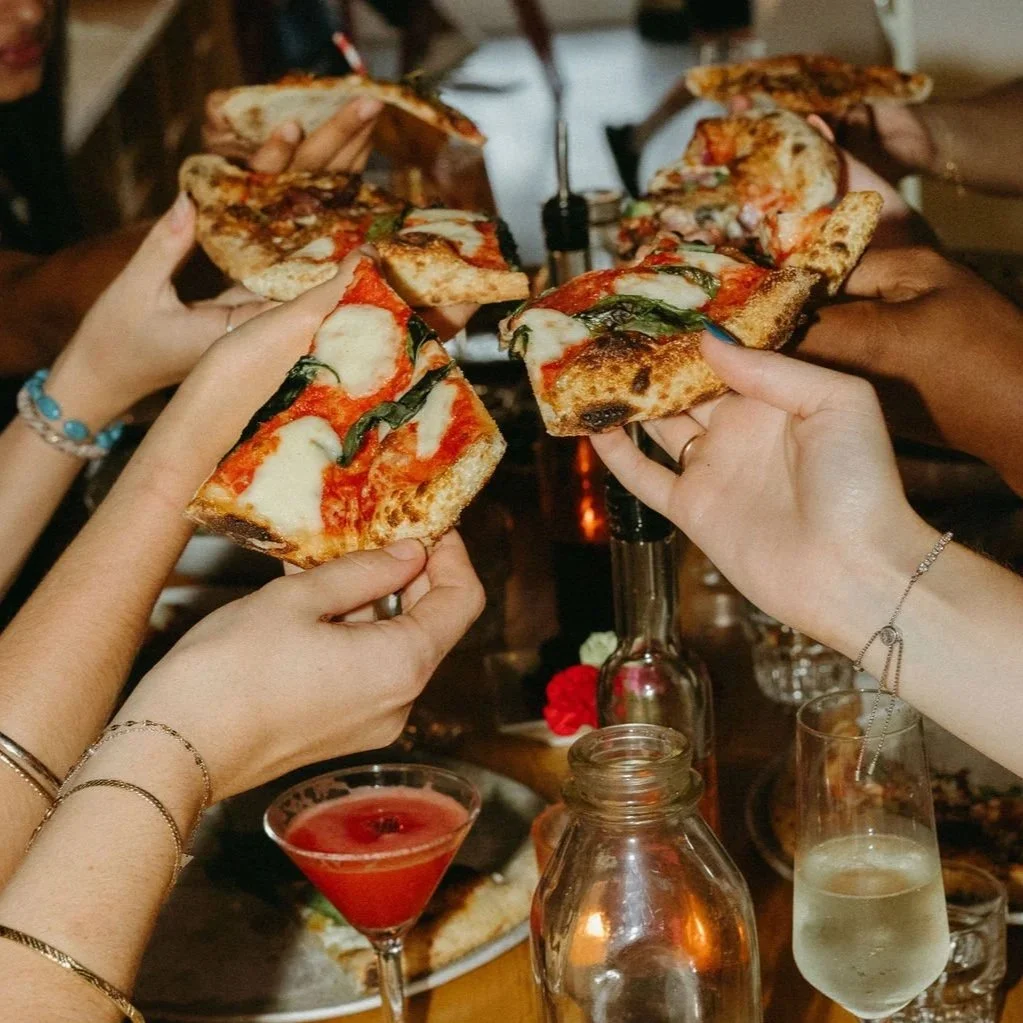 Three slices of pizza in open boxes; one with cheese and basil, one with mushrooms, black olives, ham, and artichokes, and one with bacon, sausage, and spinach.