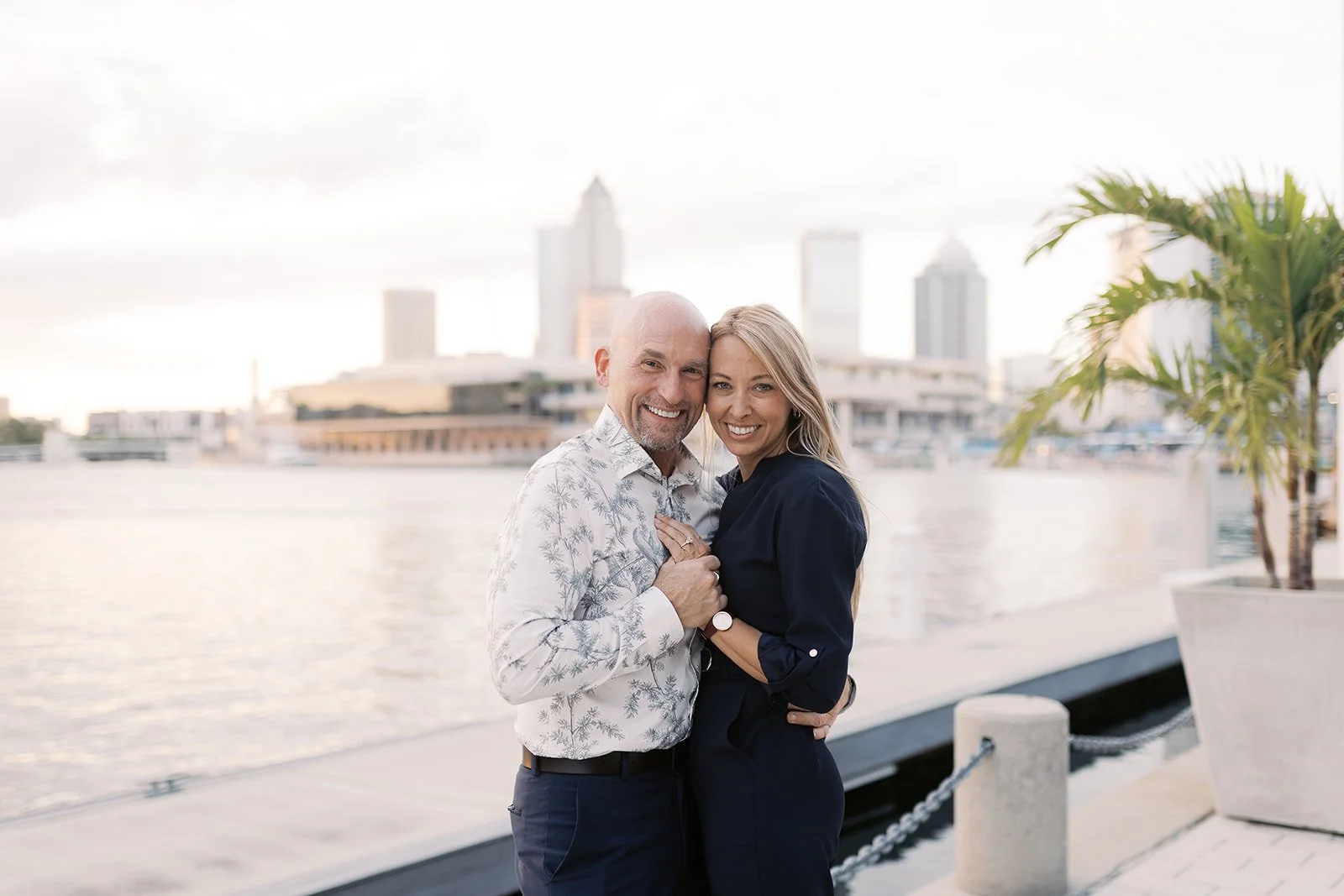 Smiling retired couple embracing on a waterfront with a city skyline, representing financial security and retirement income planning.