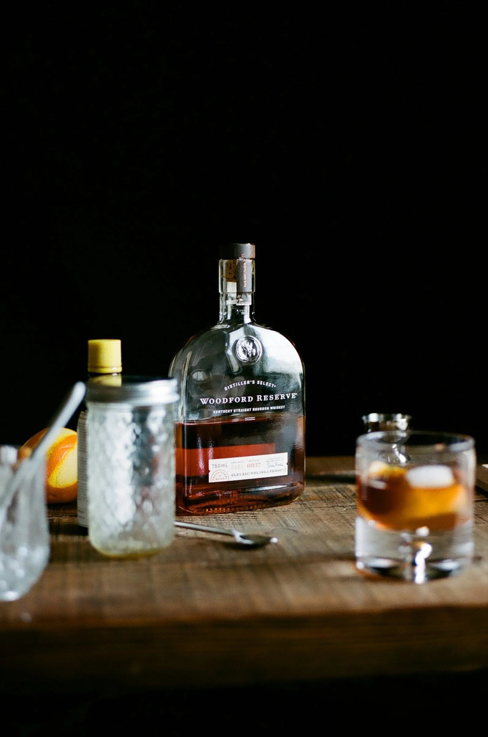 Woodford Reserve bourbon and old fashioned cocktail ingredients on a wooden bar