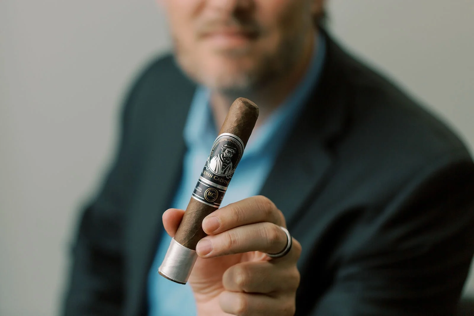 Close-up of a John Calvin cigar held by hand — representing thoughtful consumption, Christian liberty, and legacy-inspired discipline.