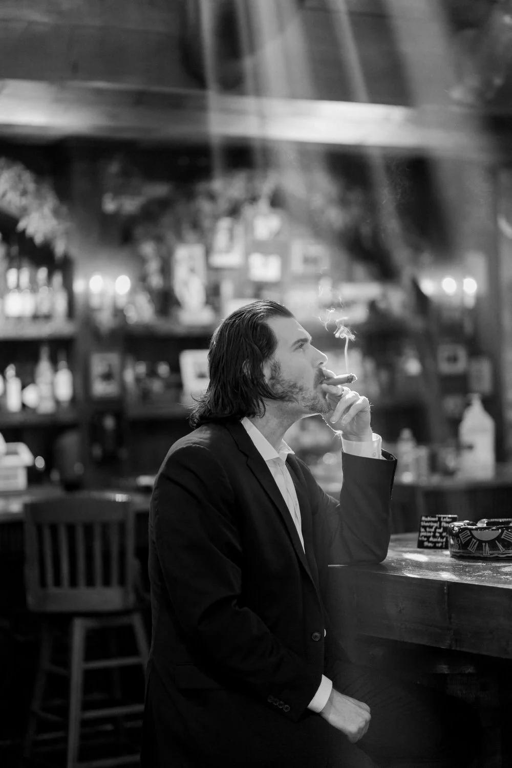 Man seated in a cigar lounge, reflecting on Scripture and stewardship — illustrating conviction and masculine headship discussed in the article.